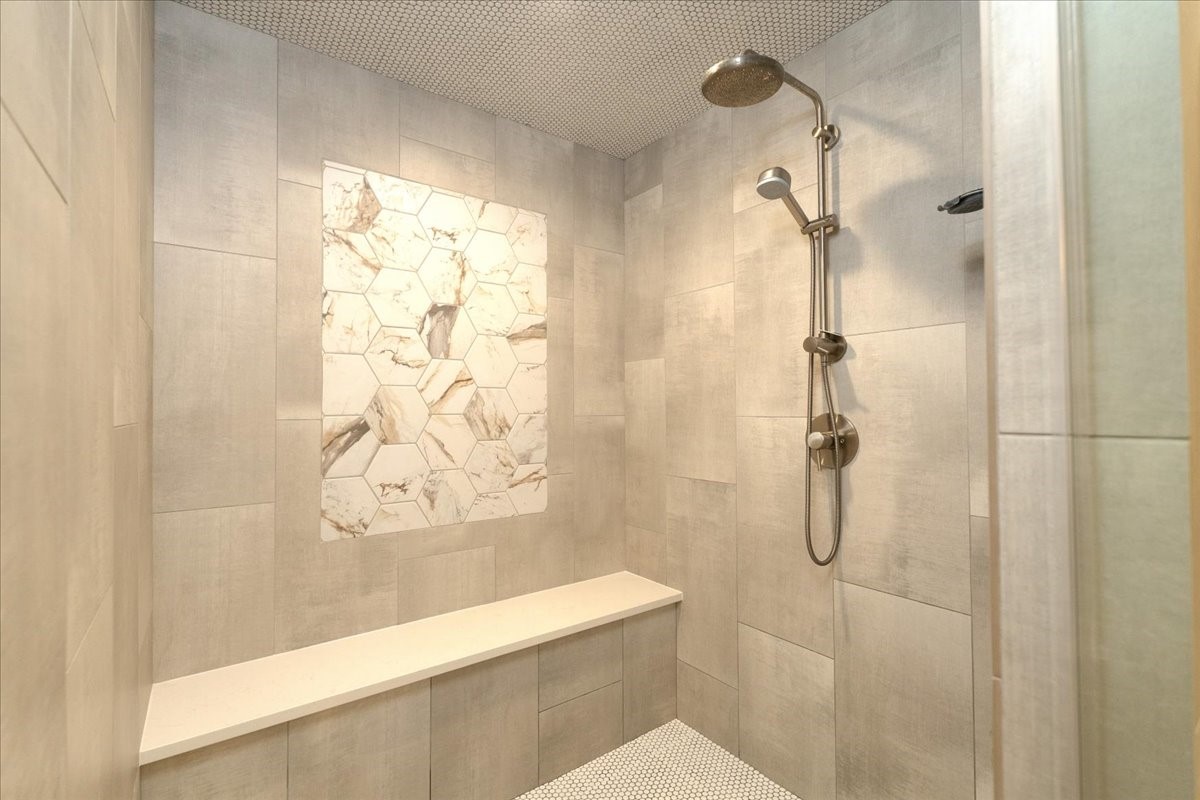 A rainfall showerhead with a handheld wand and a Canopy filter showerhead for softer hair and skin make daily routines feel effortless in this oversized walk-in shower.
