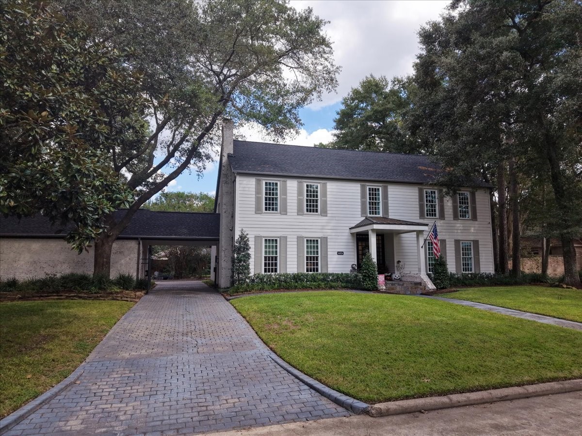 A paver driveway with a new gate (2022) leads to the covered porte cochere and three-car garage, so coming home and unloading the car stays easy, private, and out of the weather.