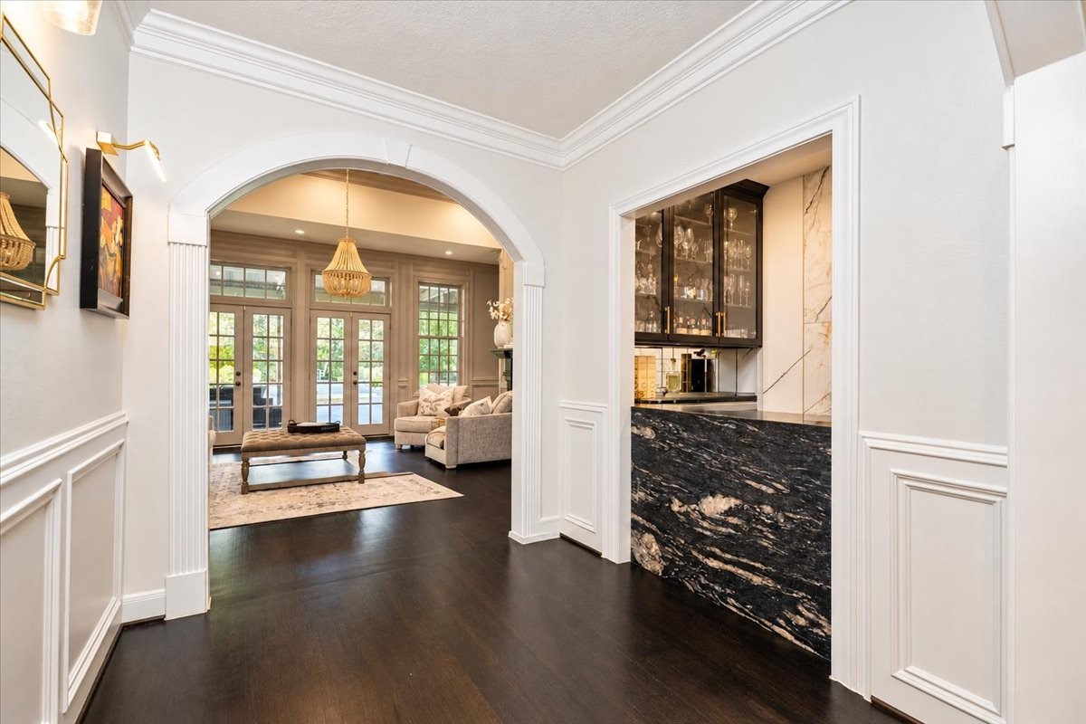 A custom bar sits off the foyer, with an arched entry leading into the living room and out to the pool and patio.