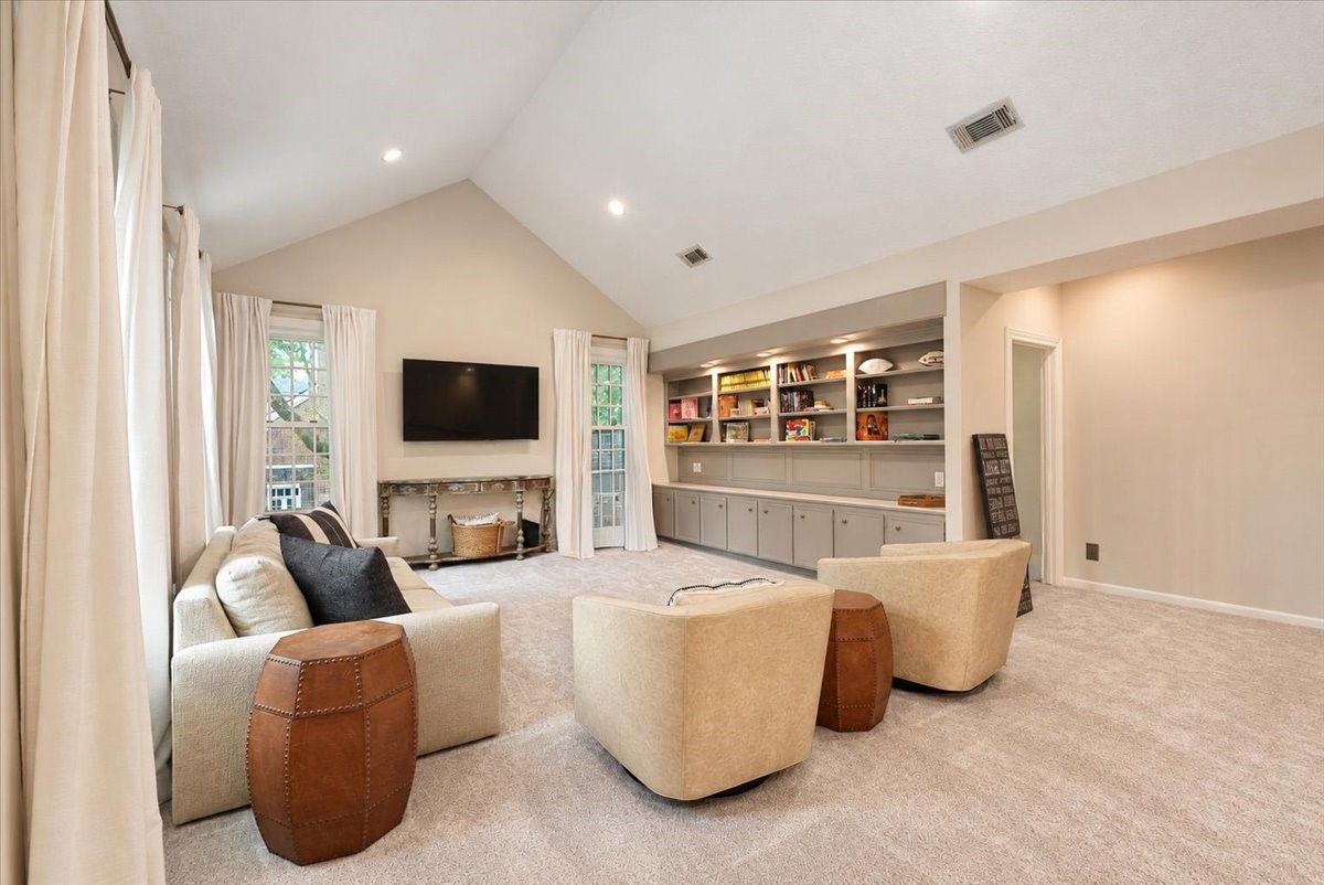 A wall of built-ins pairs open shelving with closed cabinetry below, so games, books, and keepsakes each have a place and the room stays clutter-free.