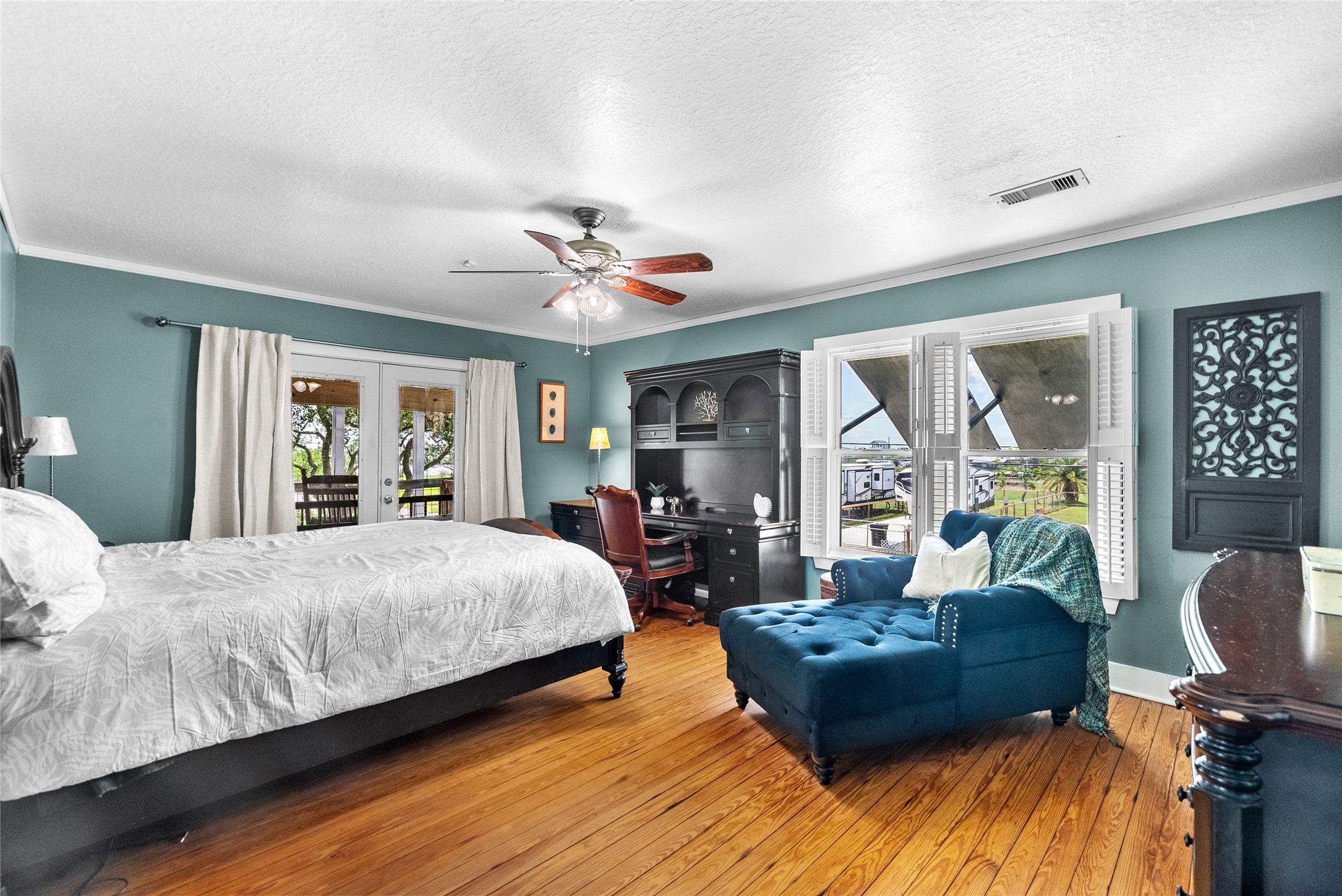 Generously sized primary suite highlighting the hardwood floors, abundant natural light, and direct outdoor access