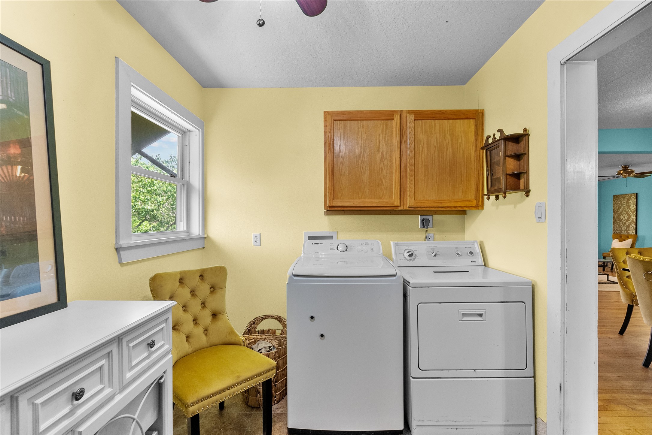 Dedicated laundry room with full-size washer and dryer connections, upper cabinetry, natural light and additional space for storage or organization