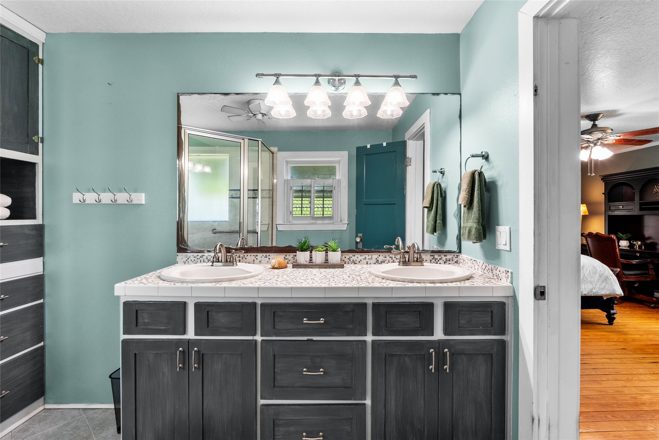 Primary bathroom offers a dual-sink vanity, extensive counter space, storage cabinetry and an oversized mirror