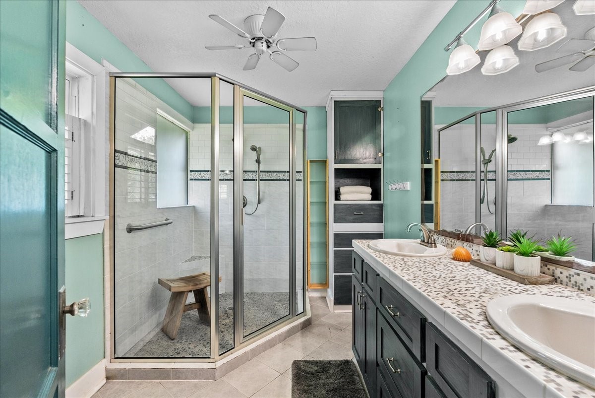 Primary bathroom features a dual-sink vanity, generous counter space, extensive cabinetry and an adjoining shower area