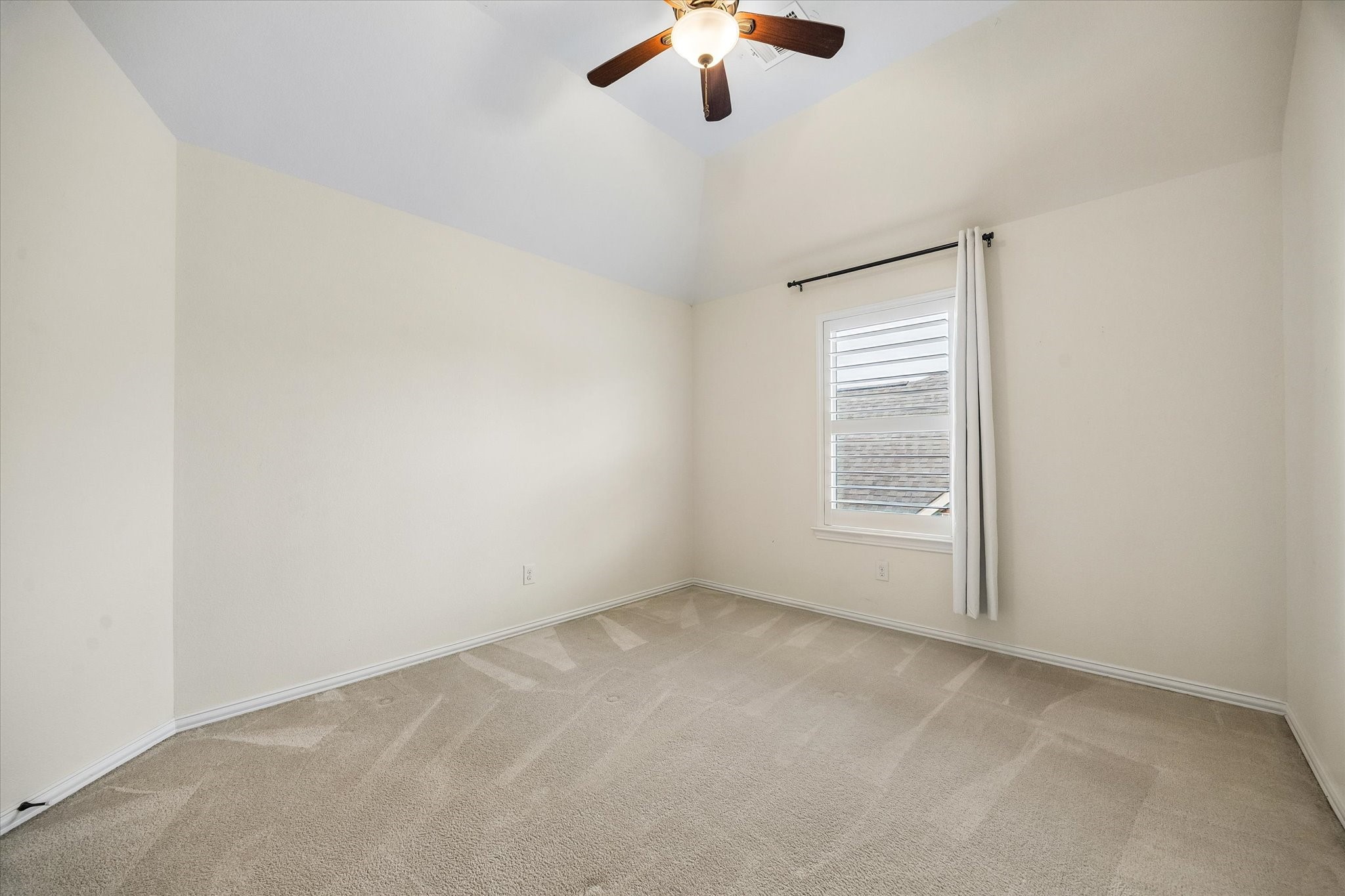Second floor guest bedroom with ceiling fan and plantation shutters.