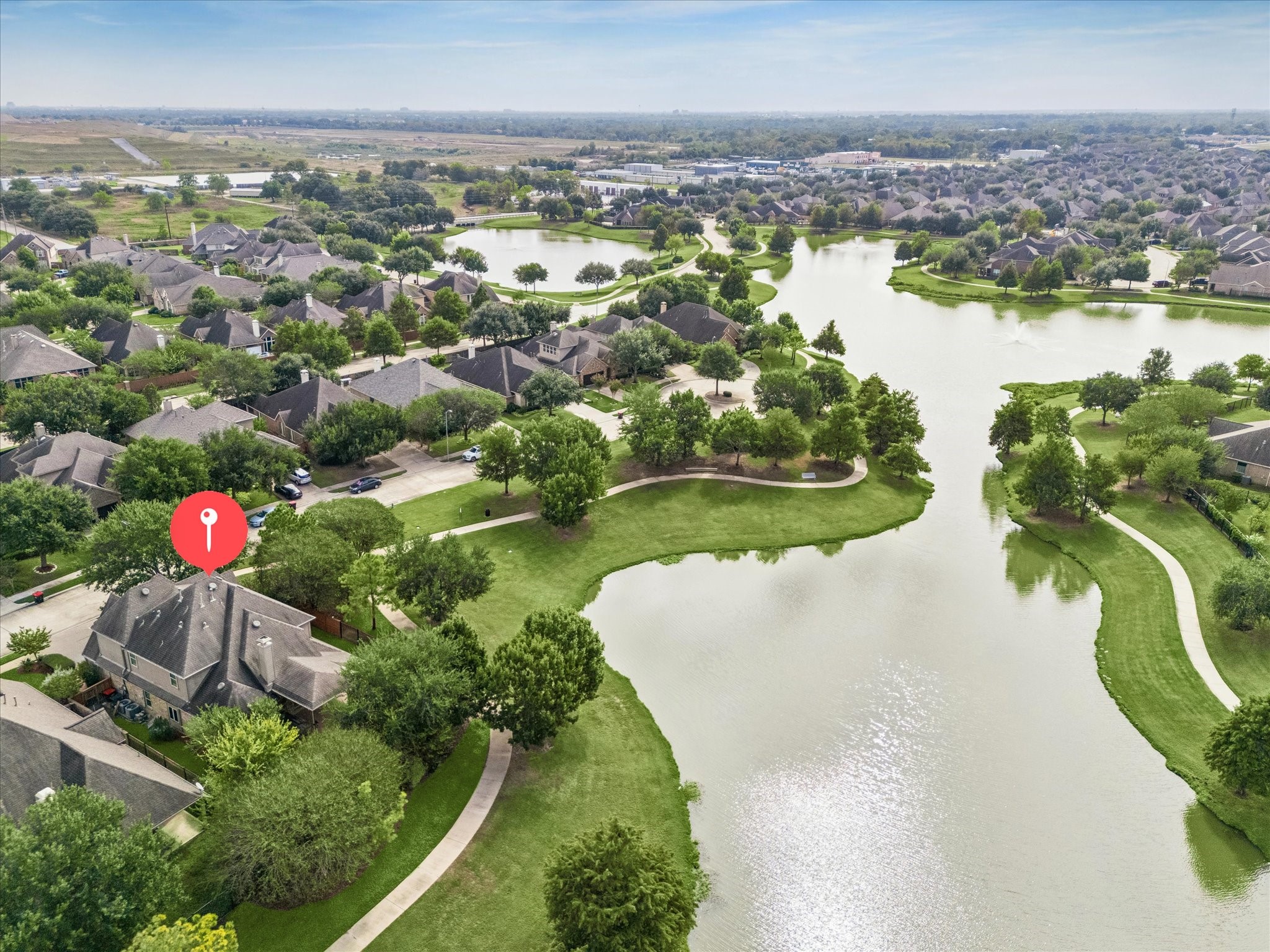 An expansive aerial perspective showcases the neighborhood lakes and winding trails, with the property marked to highlight its location beside the water and adjoining green space.