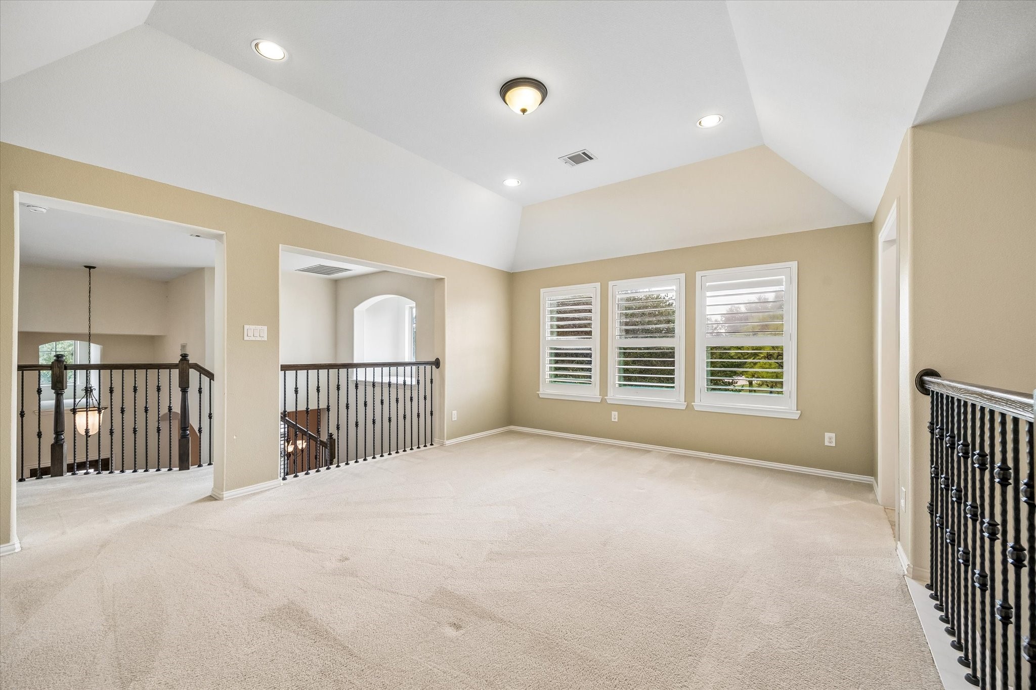 Spacious upstairs game room features a raised tray ceiling, plantation shutters, and open railings overlooking the lower level, with plenty of room for games, hobbies, or an additional living area.