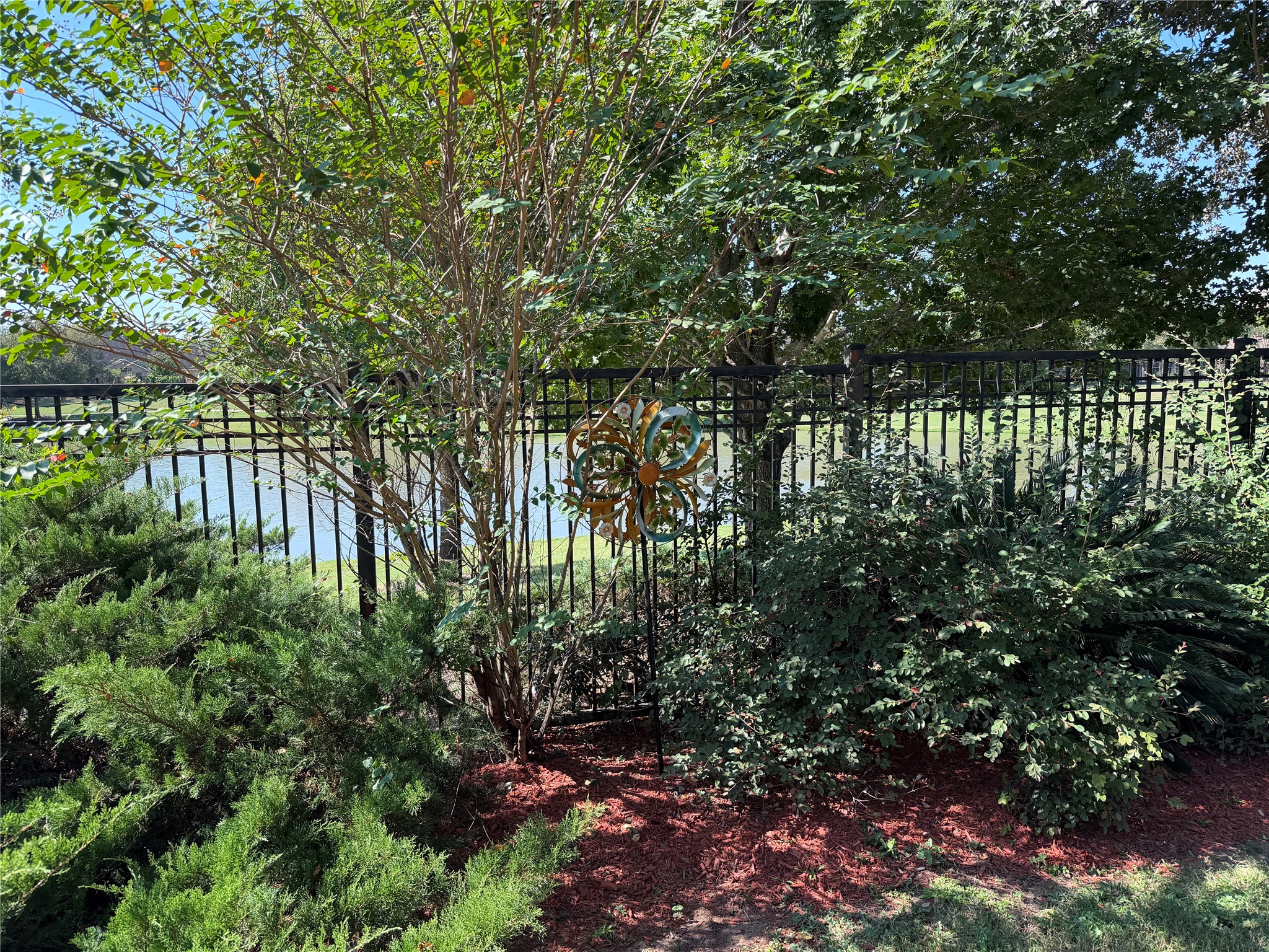 Lush landscaping and mature trees create a garden retreat, while an open iron fence preserves views of the lake.