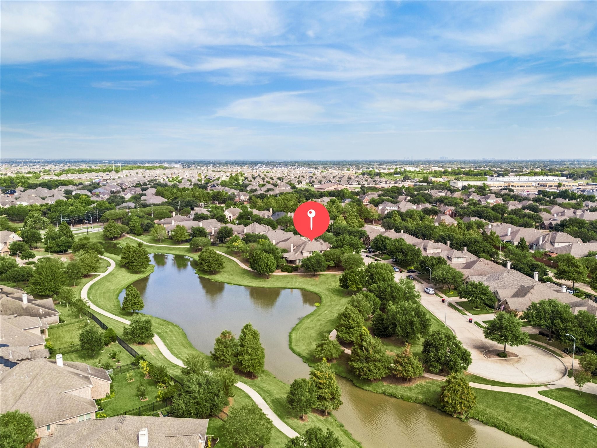 Aerial view highlights the home's scenic lakeside setting, with winding walking trails and green space extending behind and alongside the property.