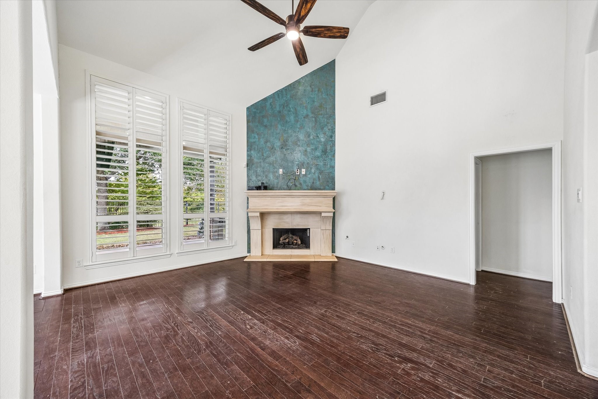 A fireplace with a handsome mantle and blue accent  wall creates a string focal point, while wide openings connect the adjacent spaces.