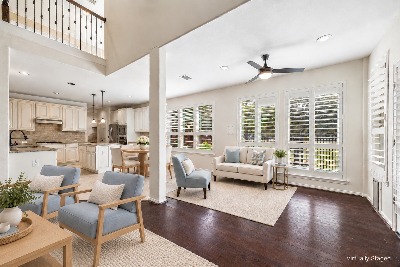 Virtually staged to showcase a welcoming sitting area with plantation shutters and wood flooring, seamlessly connected to the family room, breakfast room and kitchen.