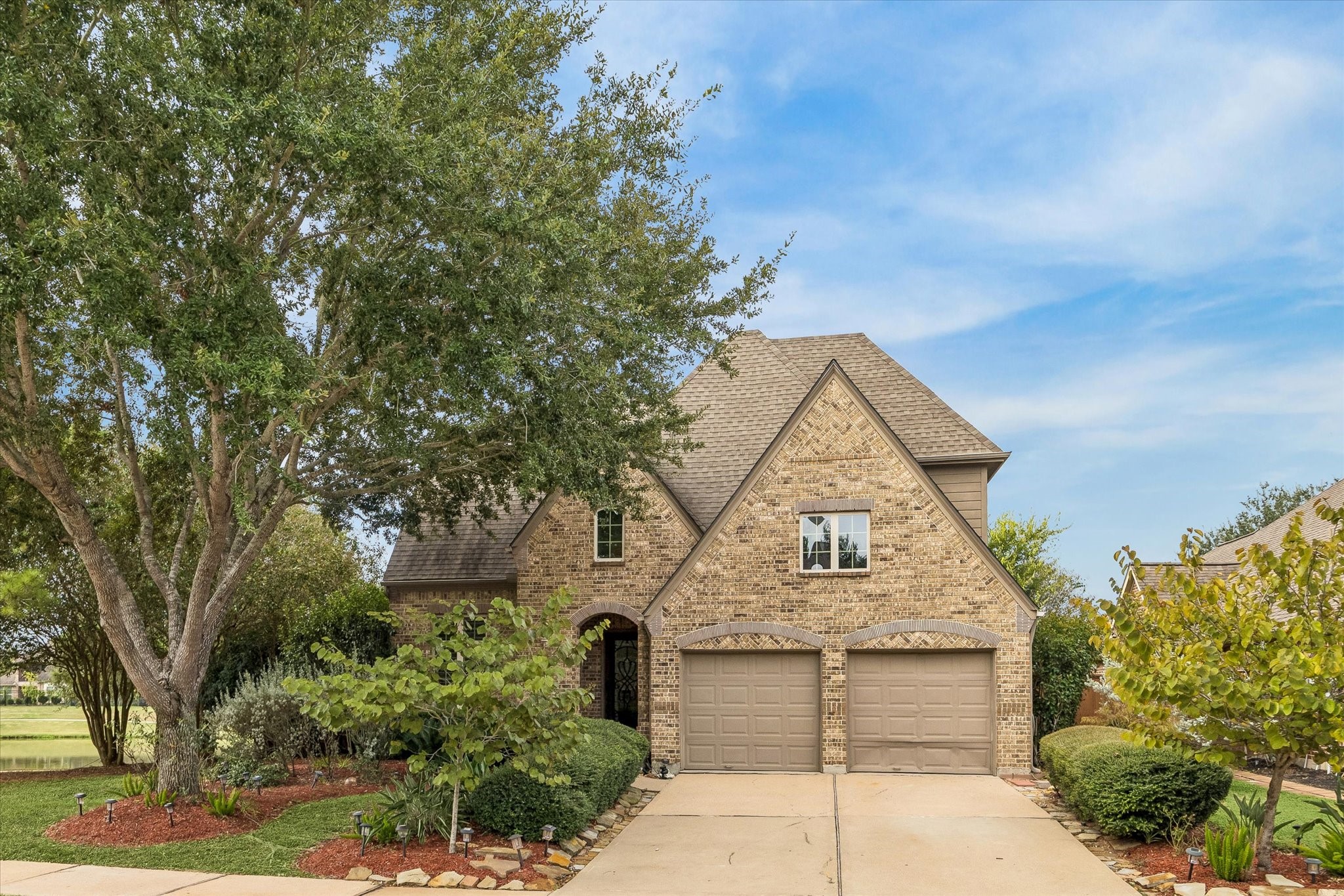 Beautifully framed by mature trees and manicured landscaping, this inviting home pairs classic brick and stone architecture with peaceful water views Beautifully framed by mature trees and manicured landscaping, this inviting home pairs classic brick and stone architecture with peaceful water views