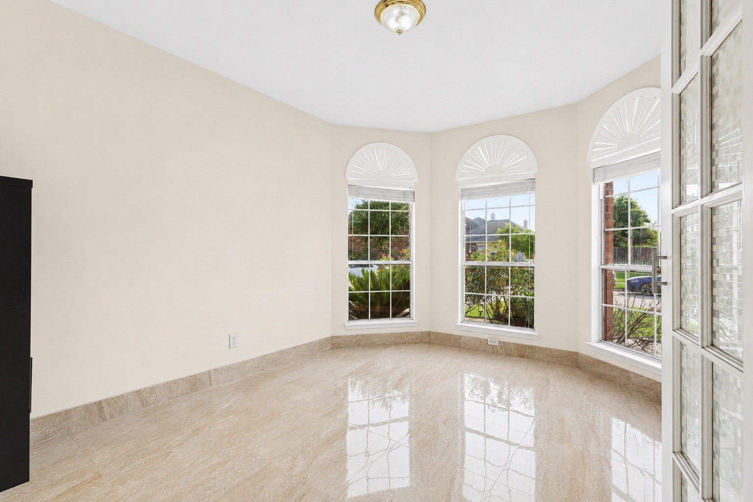 Bright room with large bay windows, offering plenty of natural light. It features a polished floor, neutral walls, and a ceiling light, creating a welcoming and spacious feel.