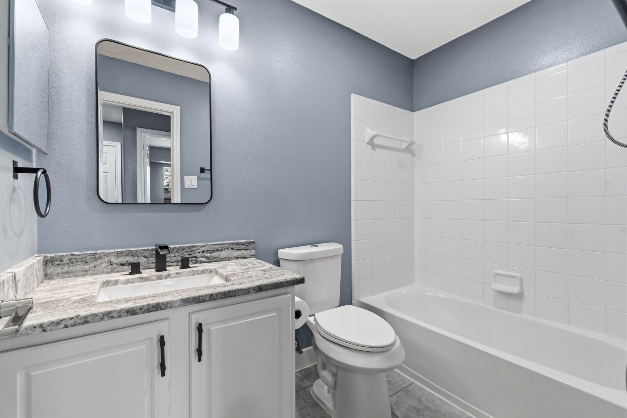 Secondary bath features granite countertops, elongated commode, designer mirror, new painted cabinets