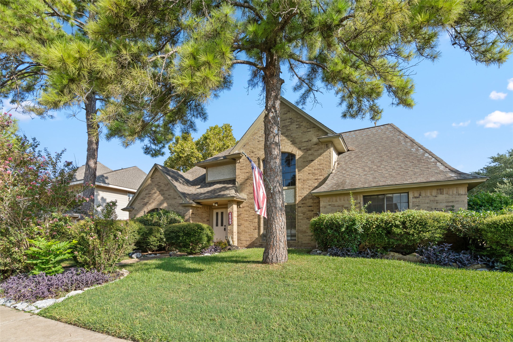 Mature trees and established greenery frame the home beautifully, creating a warm residential setting with the kind of curb appeal that makes you want to see what is inside.