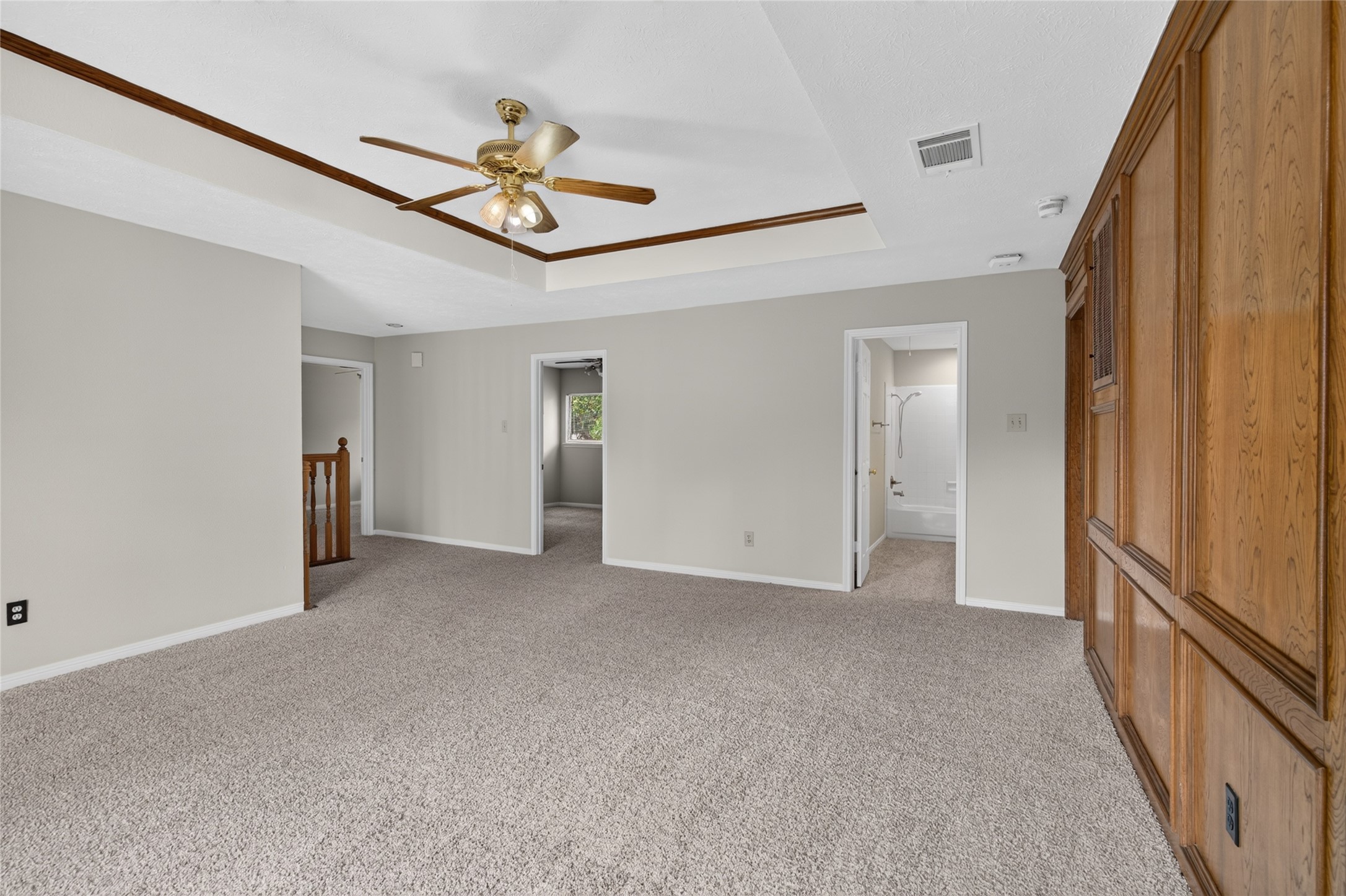 A tray ceiling, ceiling fan, carpeting, and warm wood paneling give this spacious room a comfortable atmosphere that can adapt to a variety of needs.