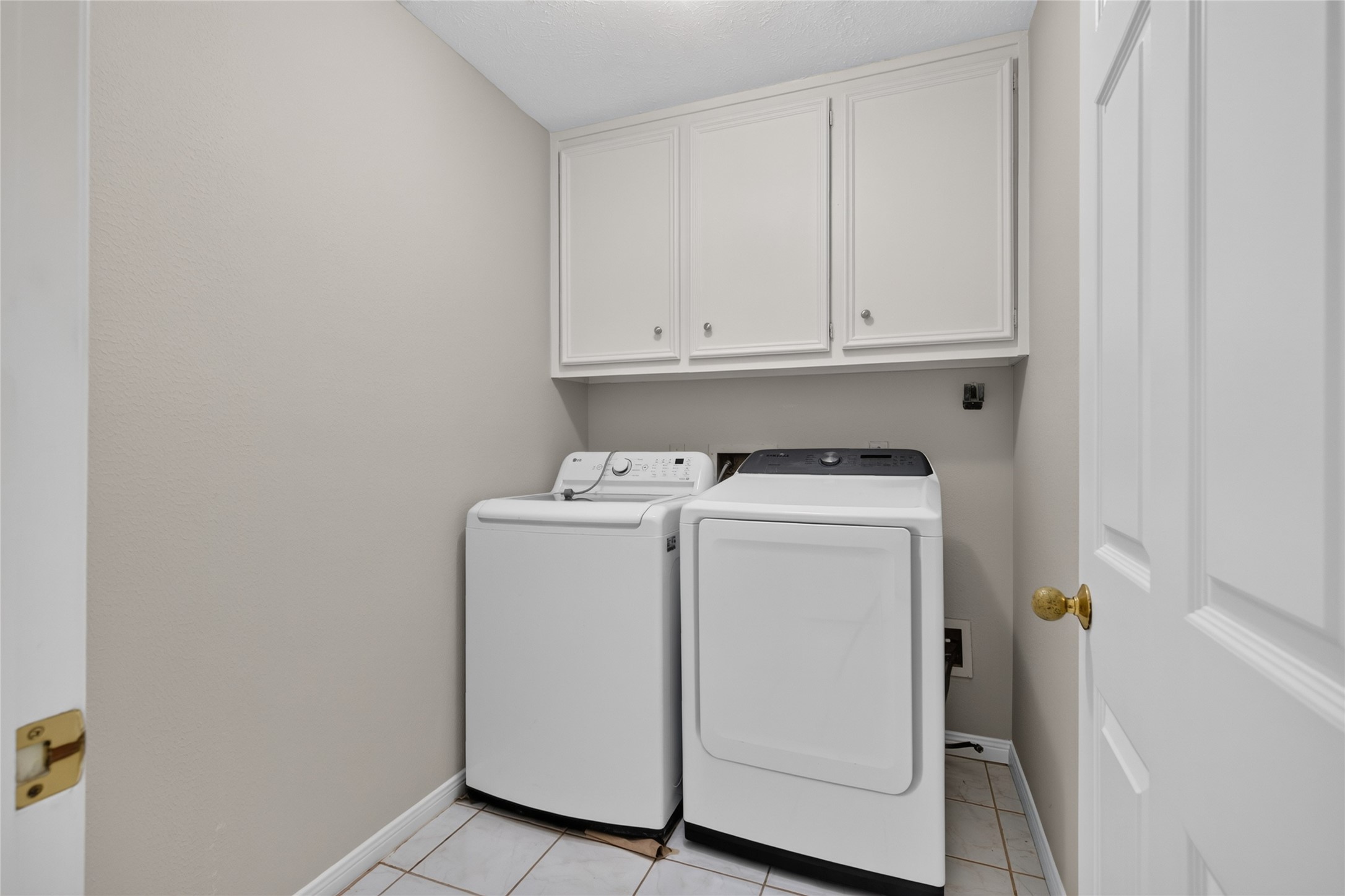 A dedicated laundry space with washer and dryer connections, overhead cabinetry, and an efficient layout keeps everyday household routines organized and convenient.