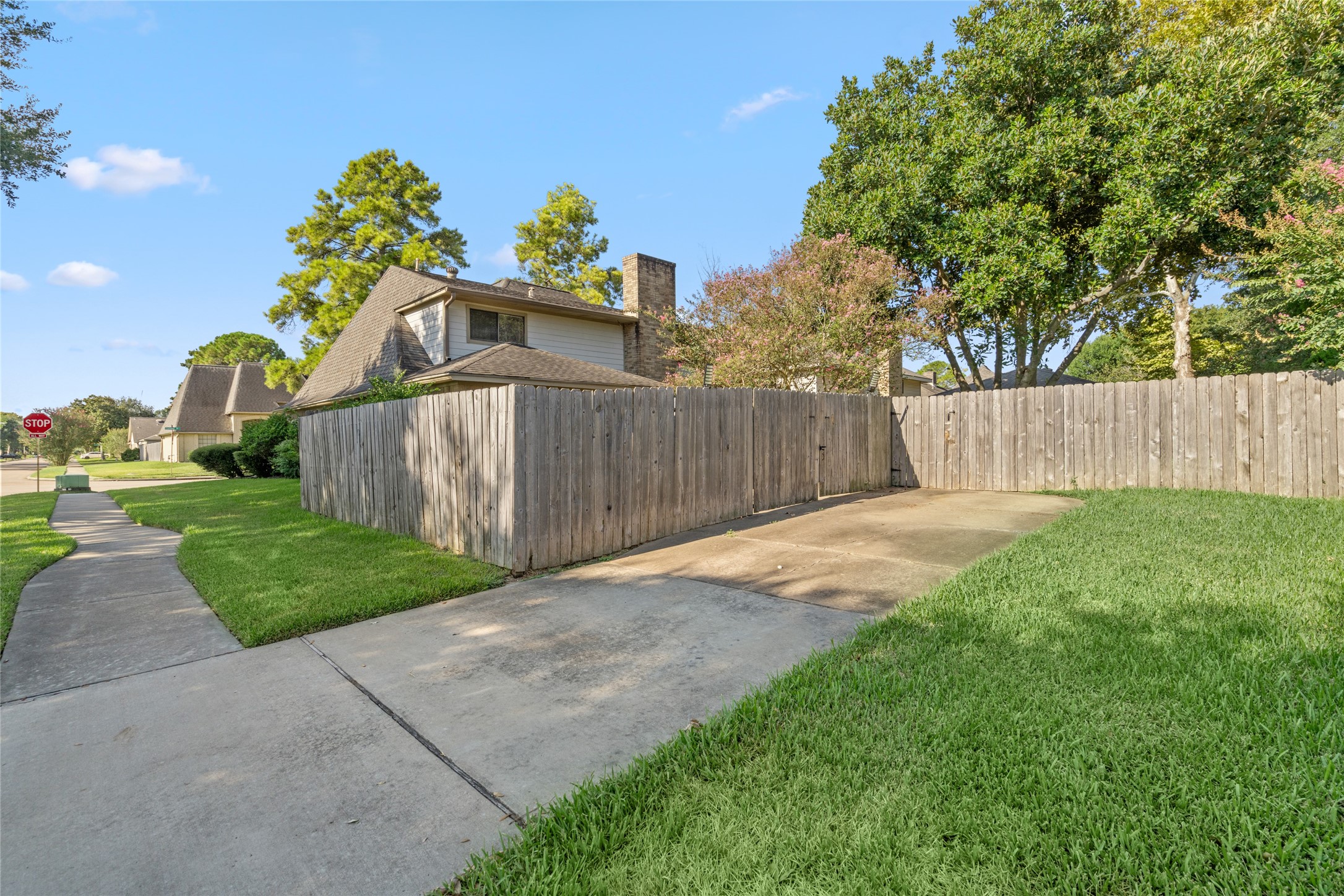 The generous driveway provides a welcoming approach to the home while mature greenery and the wood privacy fence create a comfortable sense of separation from the surroundings.