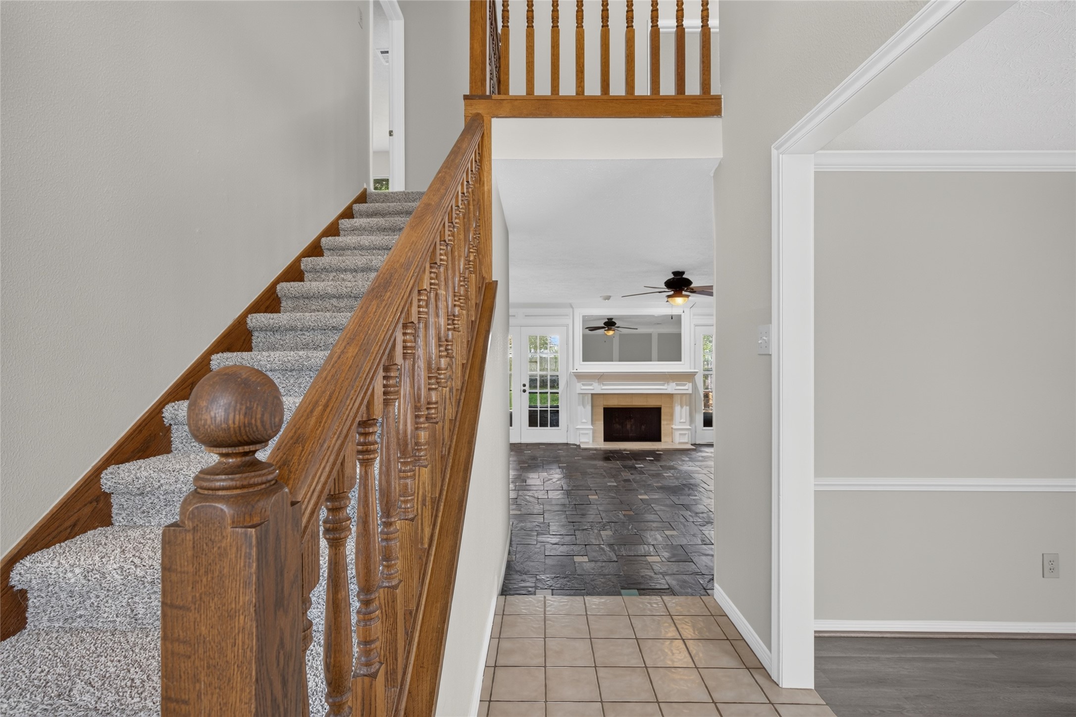 The staircase opens toward a spacious living area anchored by a fireplace, creating an attractive sense of connection between the entry and the home's main gathering spaces.