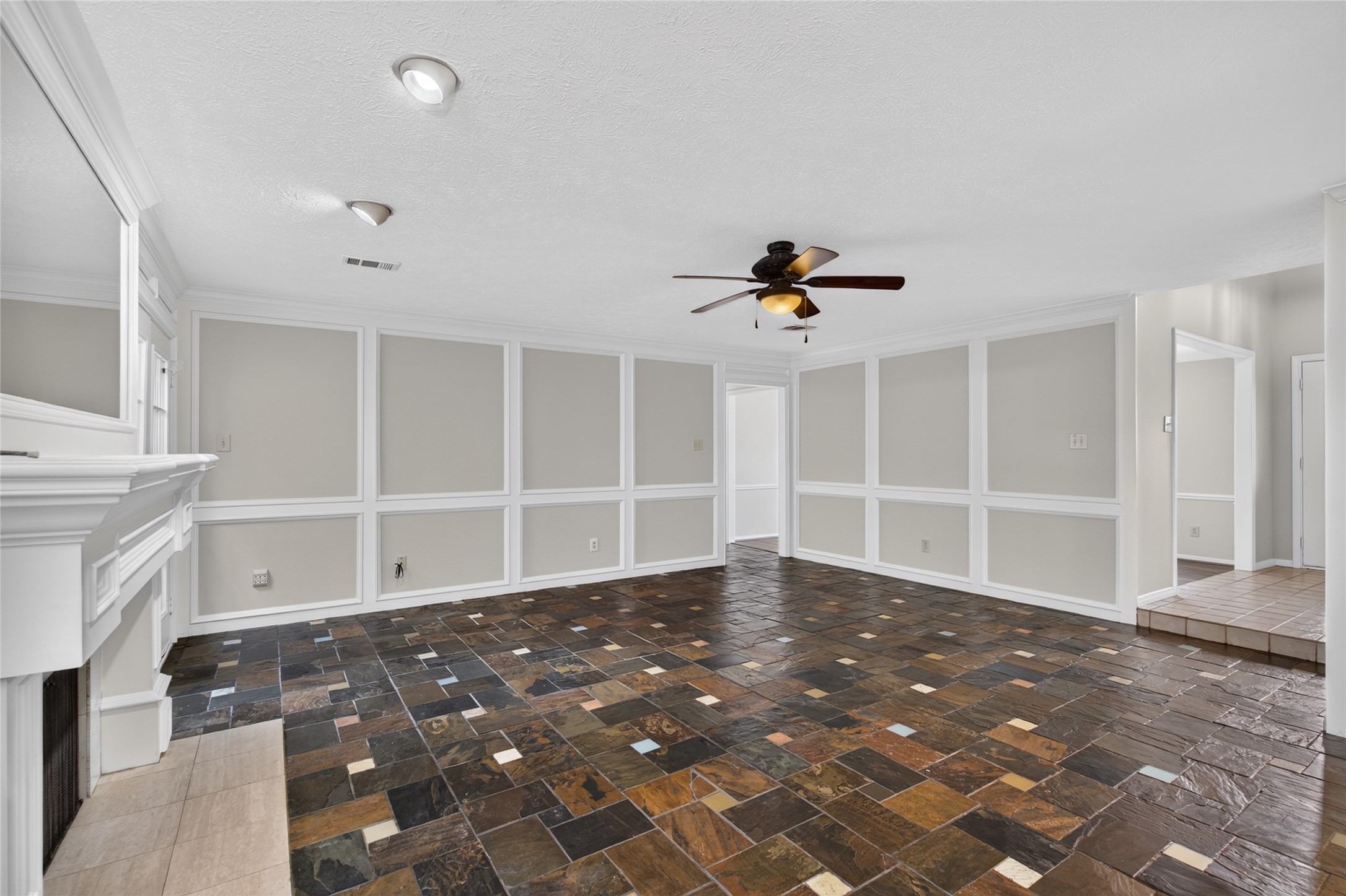 Wainscoting, tile flooring, and a central fireplace add visual character to this spacious gathering area, offering a comfortable foundation for both relaxed evenings and entertaining.