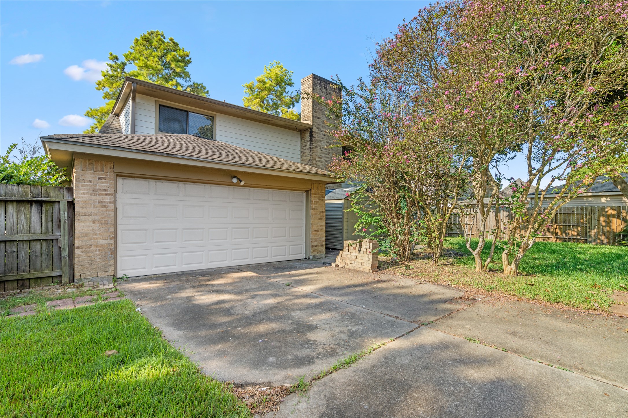 The two-story design, spacious garage, mature trees, and established yard create a private residential setting with practical outdoor appeal.