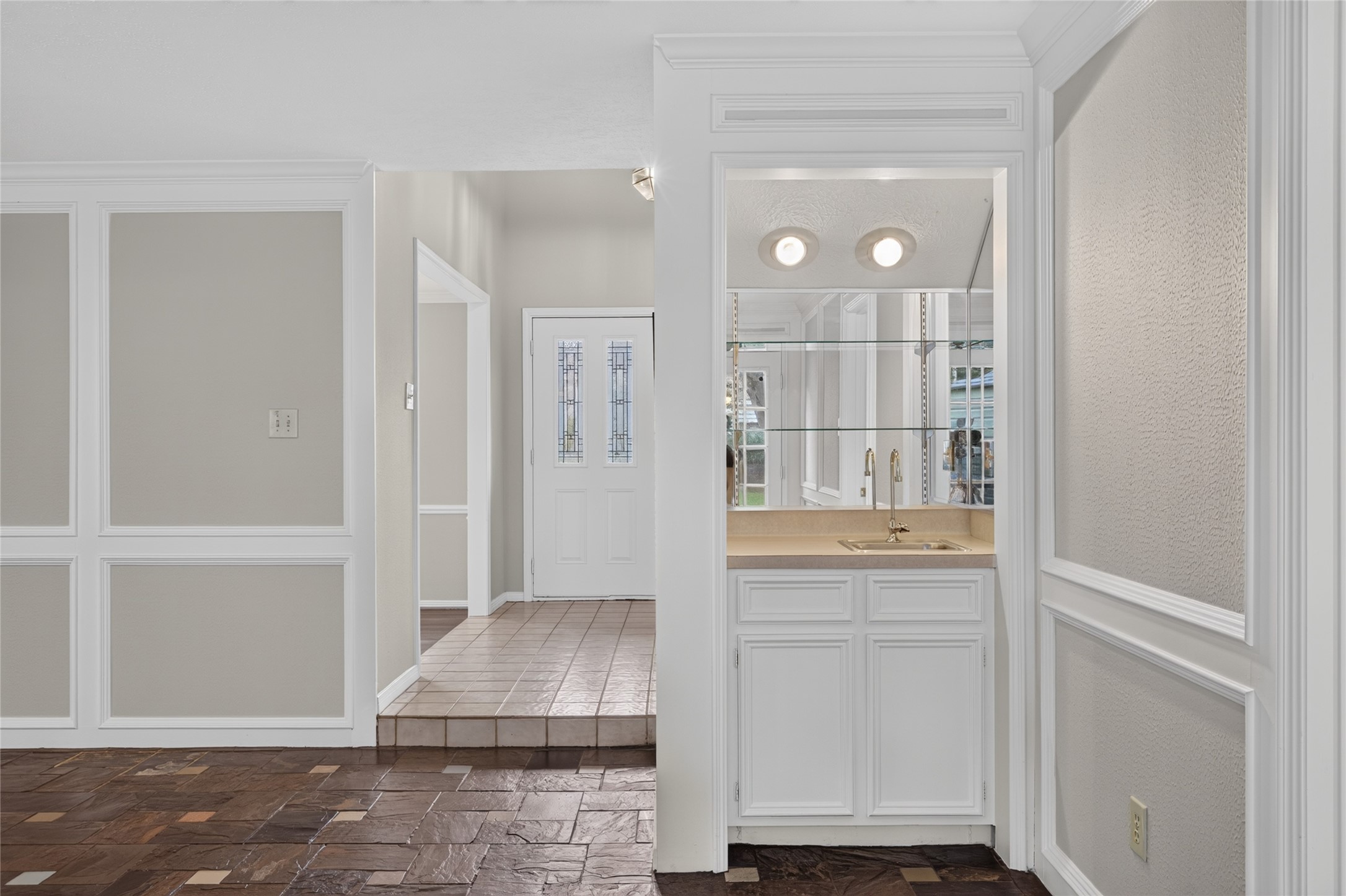 A charming built-in bar with mirrored backsplash and cabinetry creates a practical entertaining feature tucked naturally into the home's entry area.