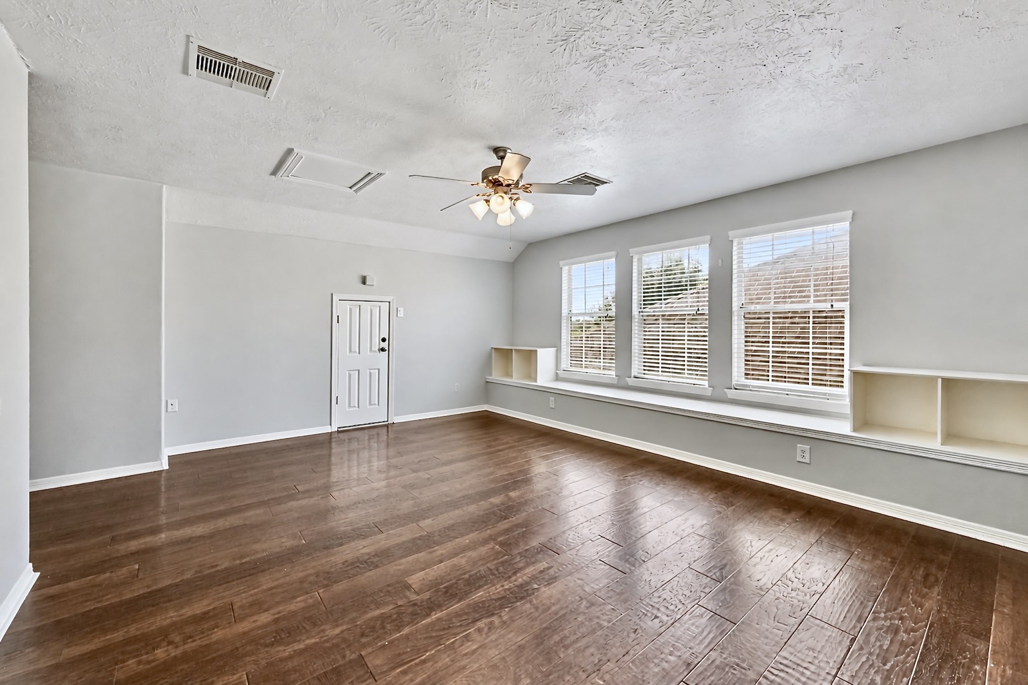 Versatile upstairs flex space with wood flooring, ceiling fan, and expansive windows. Virtually unstaged to highlight the rooms size and versatility