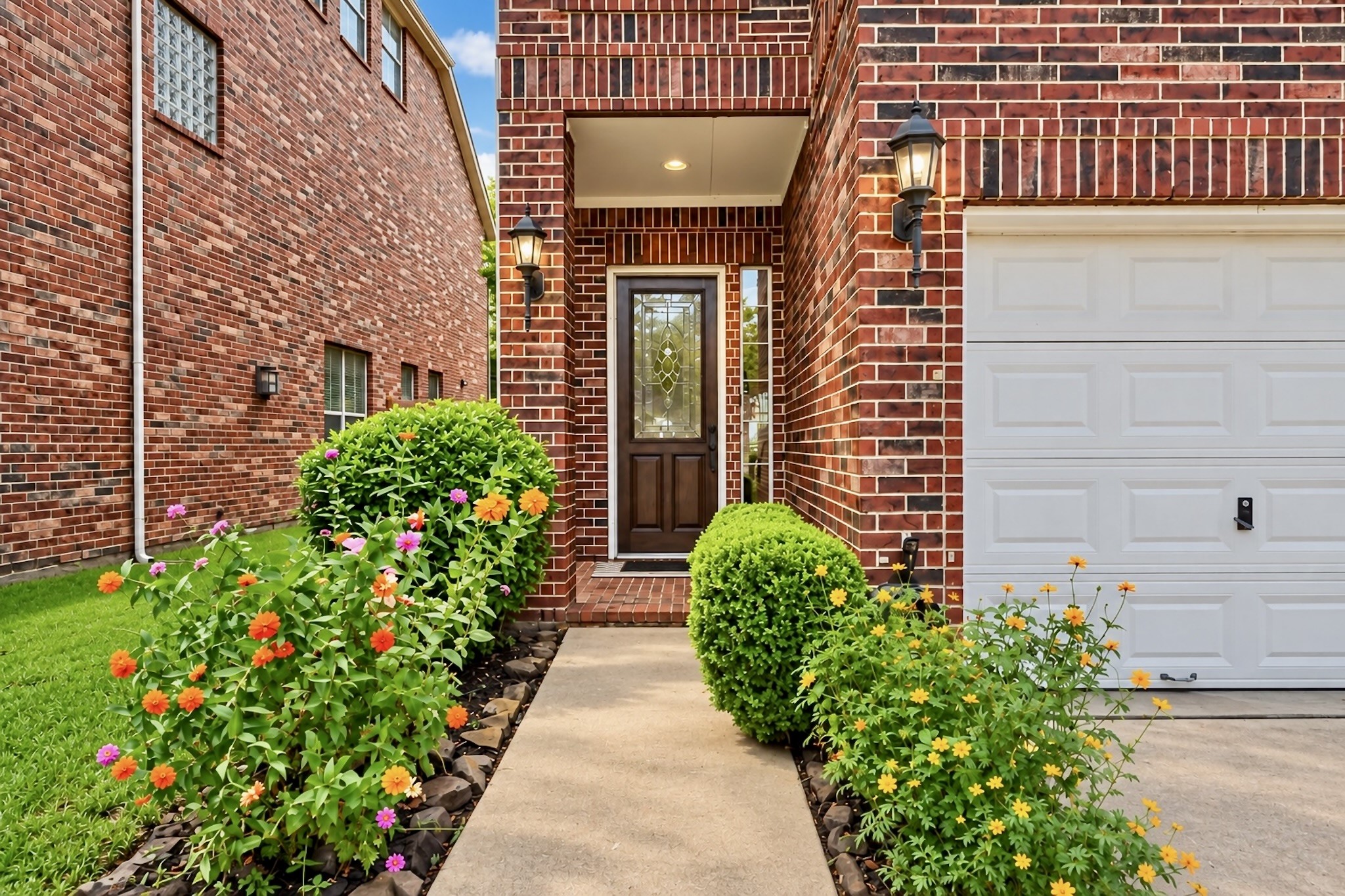 Charming front entry framed by mature landscaping and timeless brick architecture. Virtually enhanced photo.