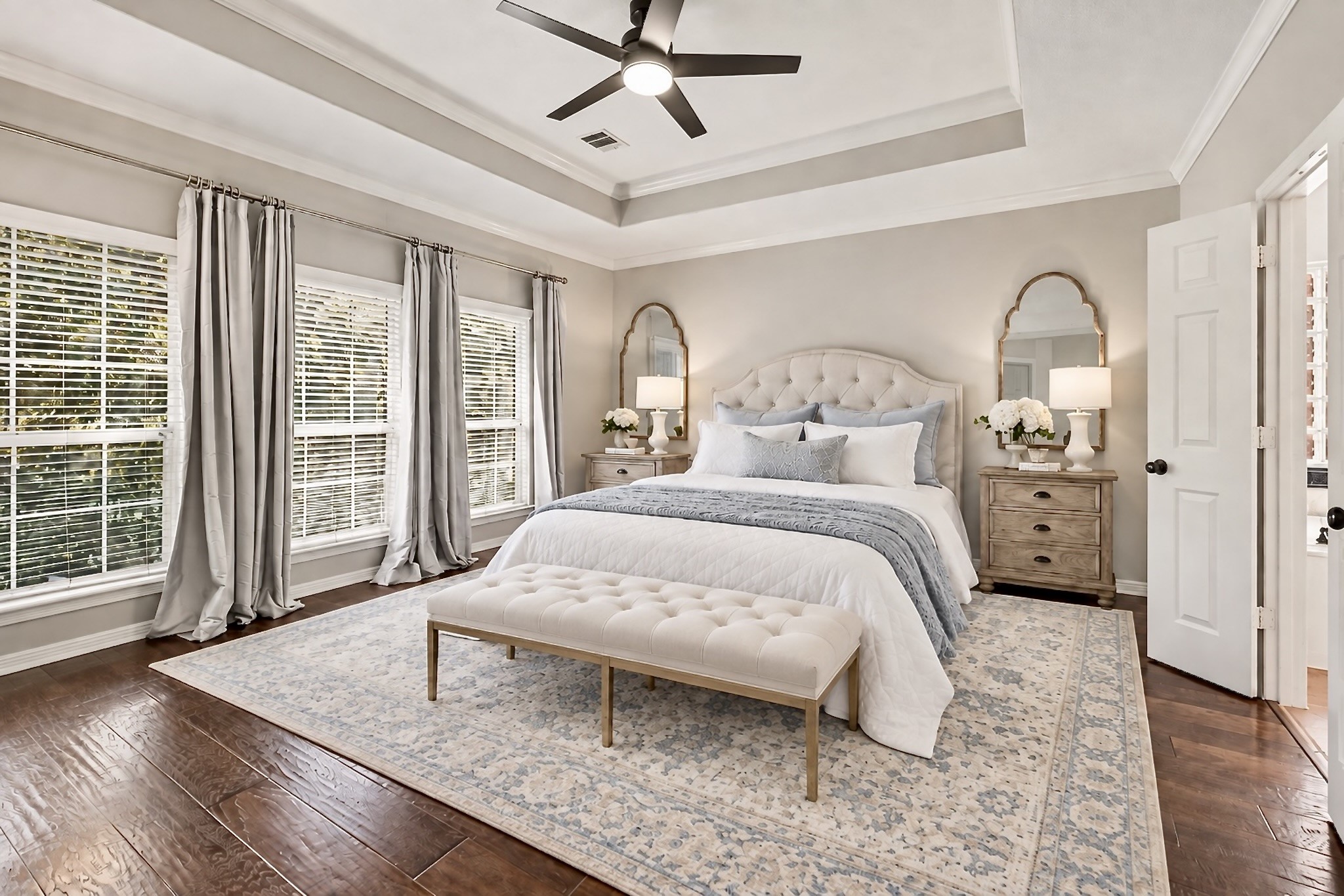 Spacious owners suite with tray ceiling, wood flooring, and soft natural light. Virtually staged Spacious owners suite with tray ceiling, wood flooring, and soft natural light. Virtually staged