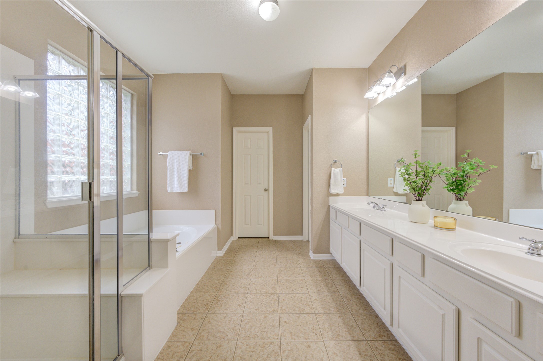 Spa-inspired primary bath with dual vanities, jetted tub, and separate shower.