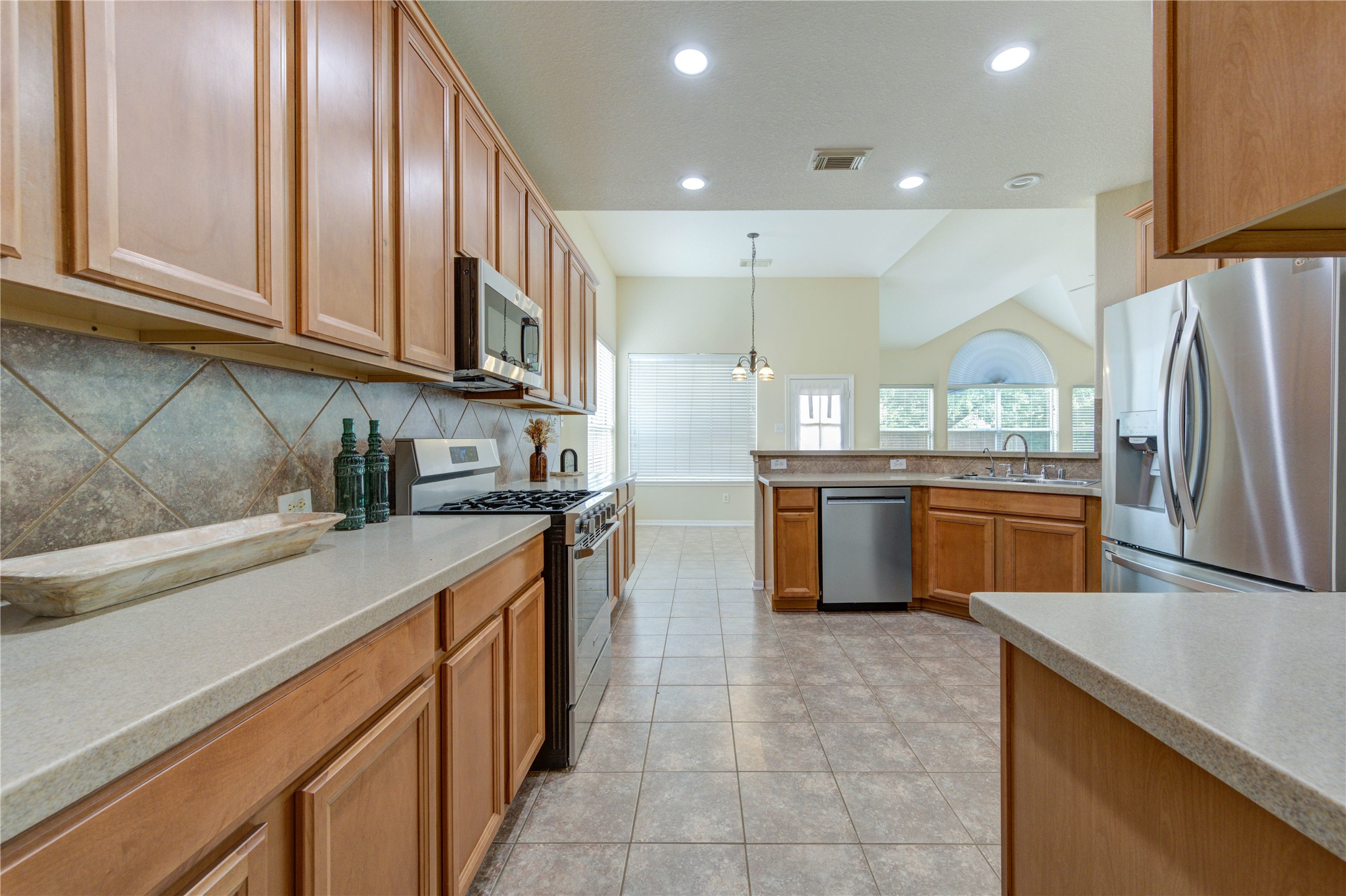 Well-appointed kitchen featuring ample cabinetry, STARON countertops, gas cooking, and an open-concept layout flowing seamlessly into the breakfast and living areas. Complete with updated stainless steel appliances.