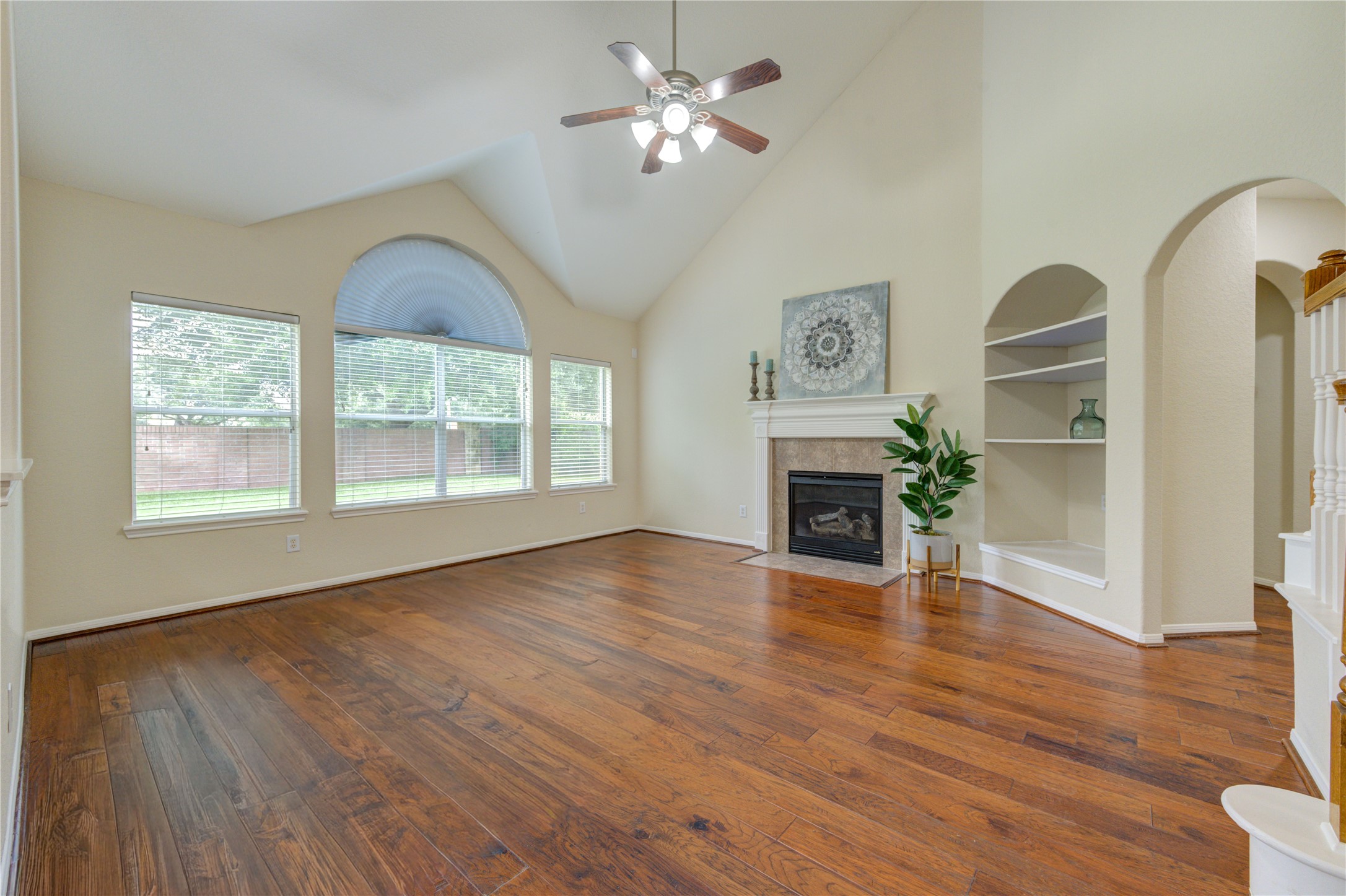 Bright and inviting living room with rich wood flooring, abundant natural light, and a cozy fireplace. Bright and inviting living room with rich wood flooring, abundant natural light, and a cozy fireplace.