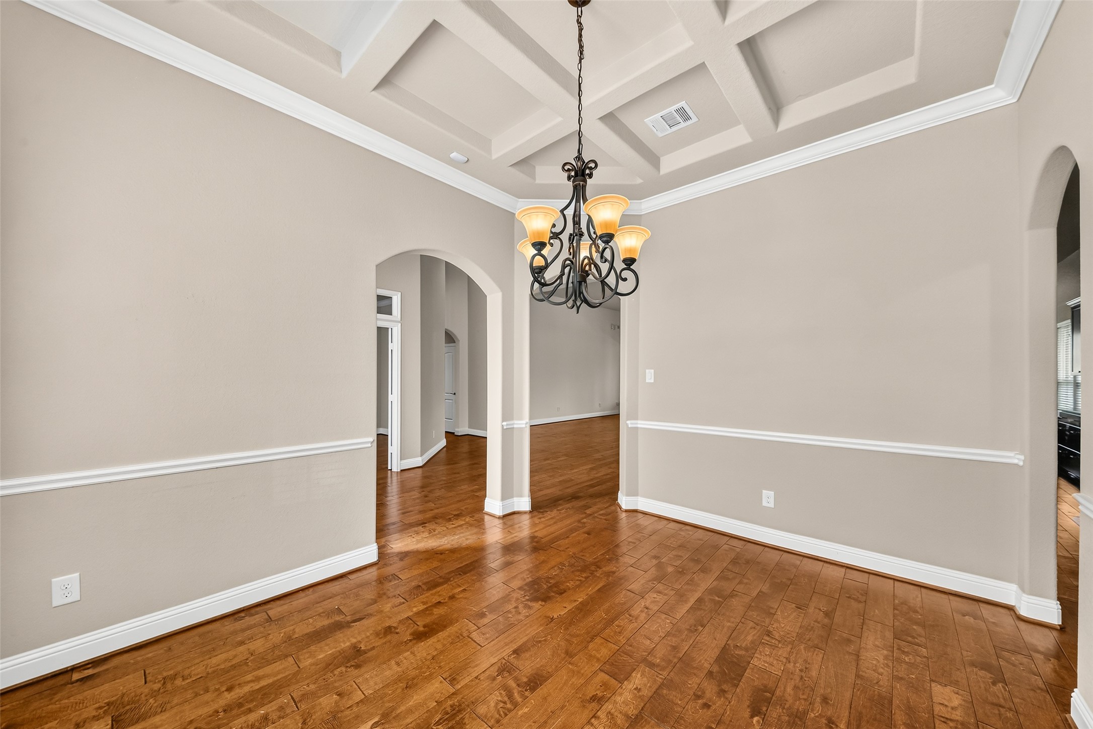 As you enter you are greeted with an elegant dining room featuring a coffered ceiling, and rich hardwood floors, creating a warm and inviting atmosphere.