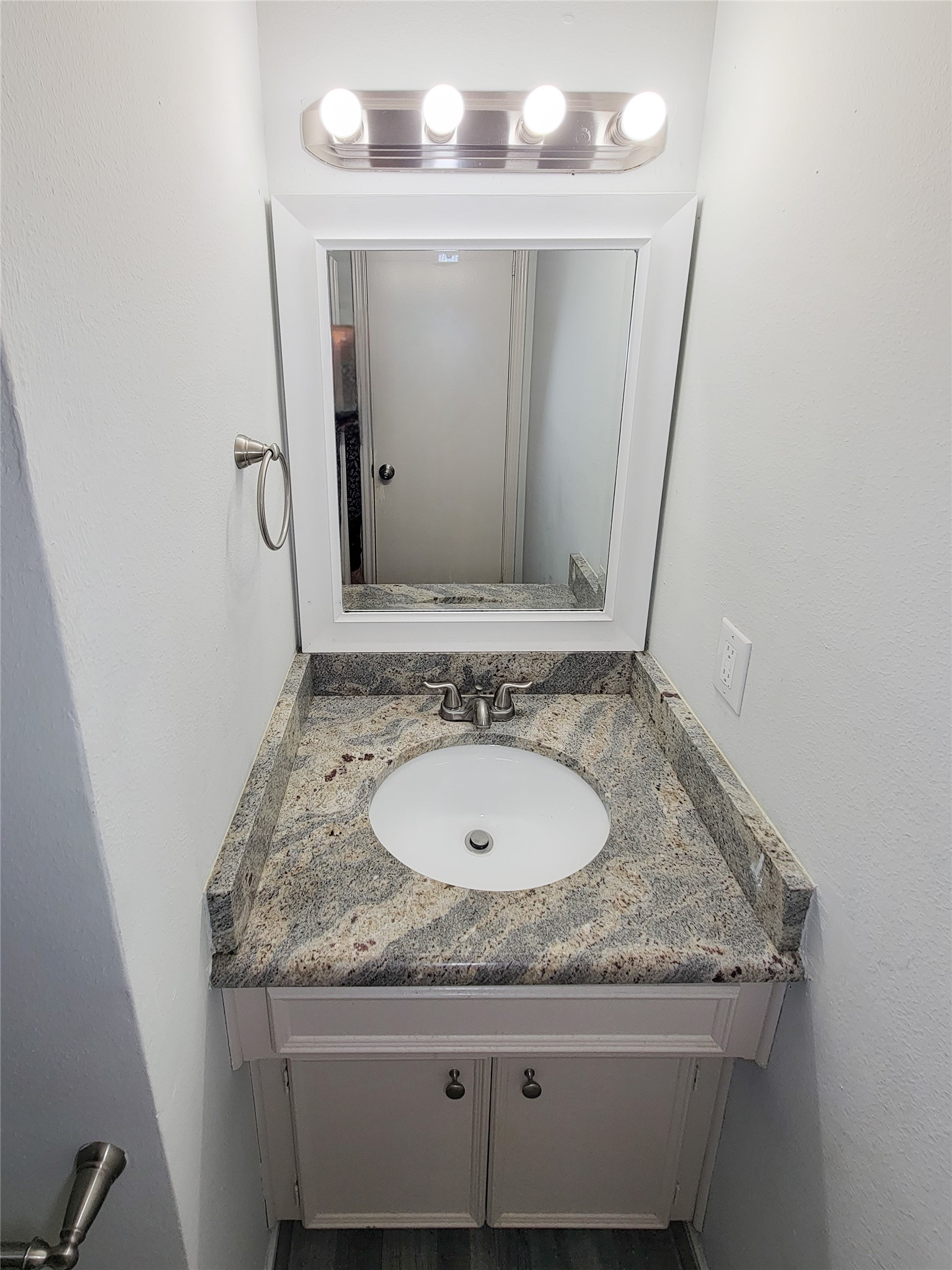 Charming bathroom with a sleek granite countertop vanity, modern faucet, and bright lighting, creating a clean and inviting space.