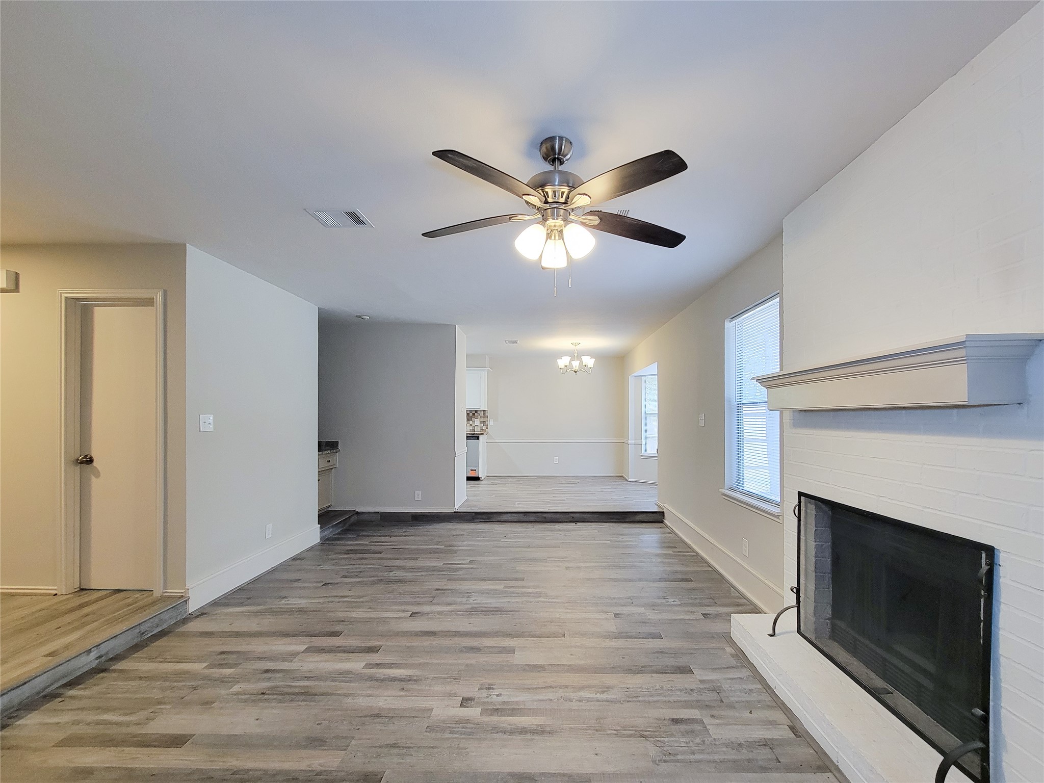 Spacious living area with elegant wood flooring, a cozy fireplace, and ample natural light from large windows, seamlessly leading into the dining space.