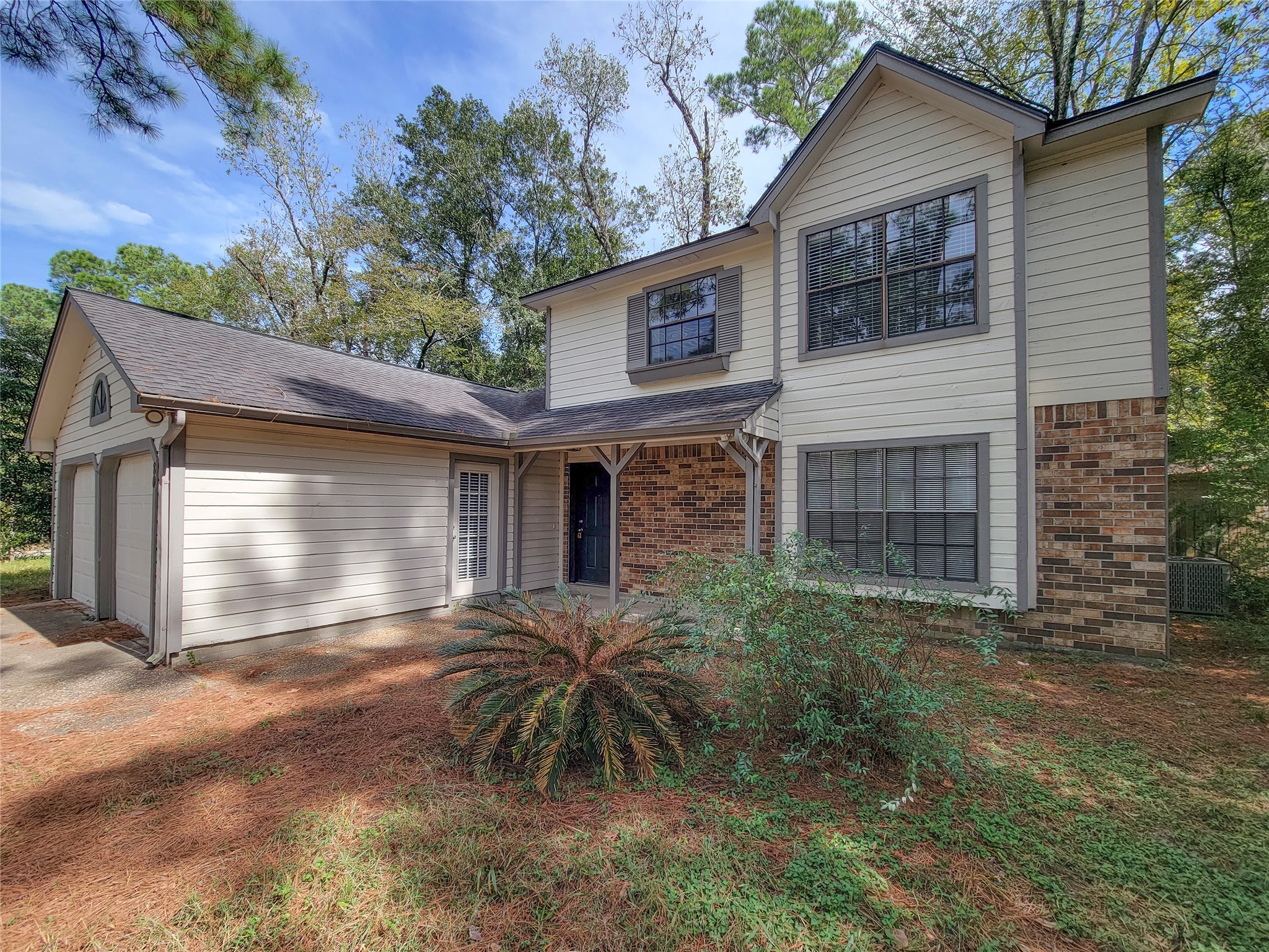 Charming two-story home with a mix of brick and siding, featuring a spacious attached garage and surrounded by lush greenery for added privacy. Charming two-story home with a mix of brick and siding, featuring a spacious attached garage and surrounded by lush greenery for added privacy.