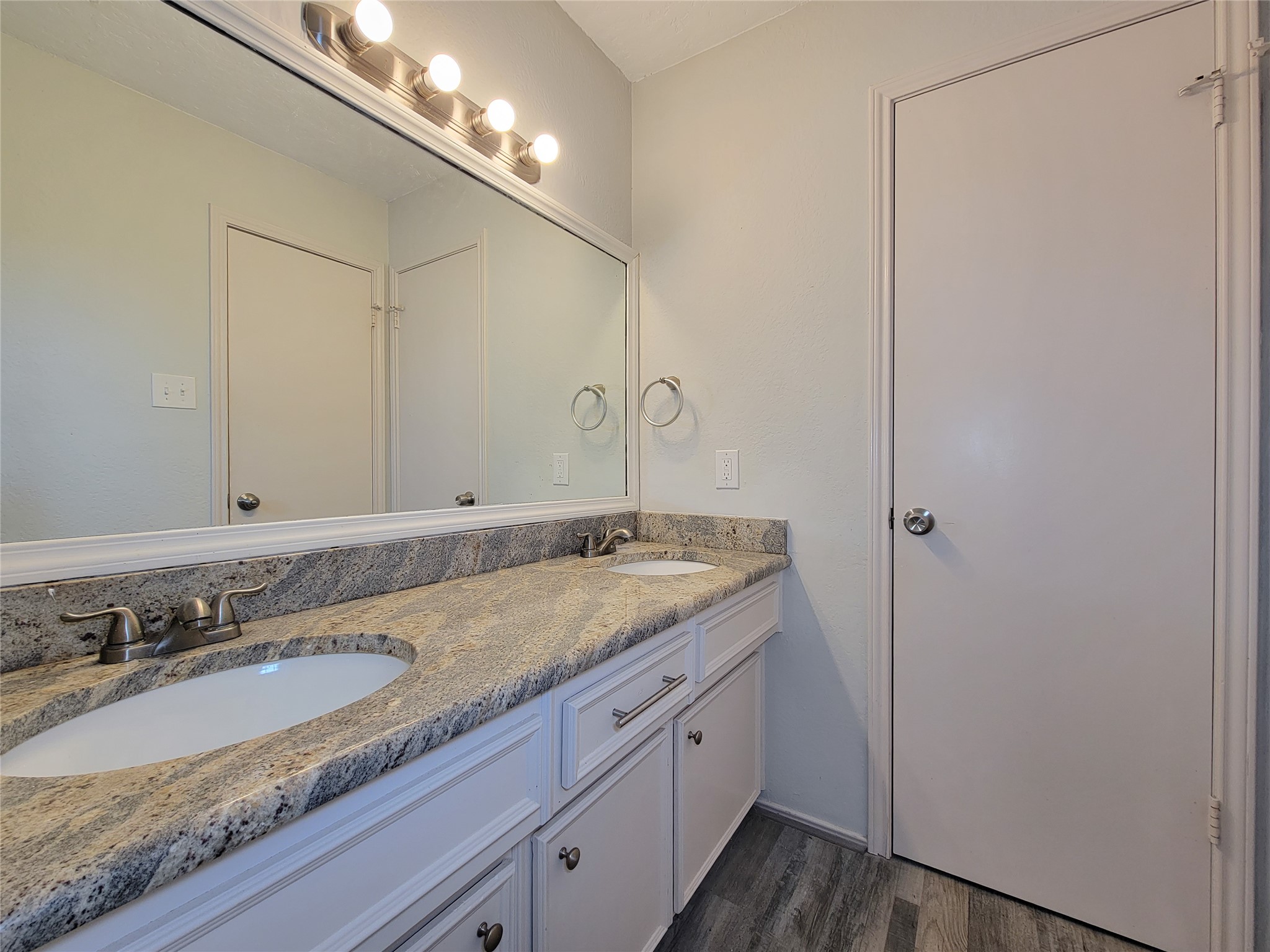 Elegant bathroom featuring a spacious dual-sink vanity with sleek granite countertops, modern fixtures, and a large mirror, all set against stylish flooring. Elegant bathroom featuring a spacious dual-sink vanity with sleek granite countertops, modern fixtures, and a large mirror, all set against stylish flooring.
