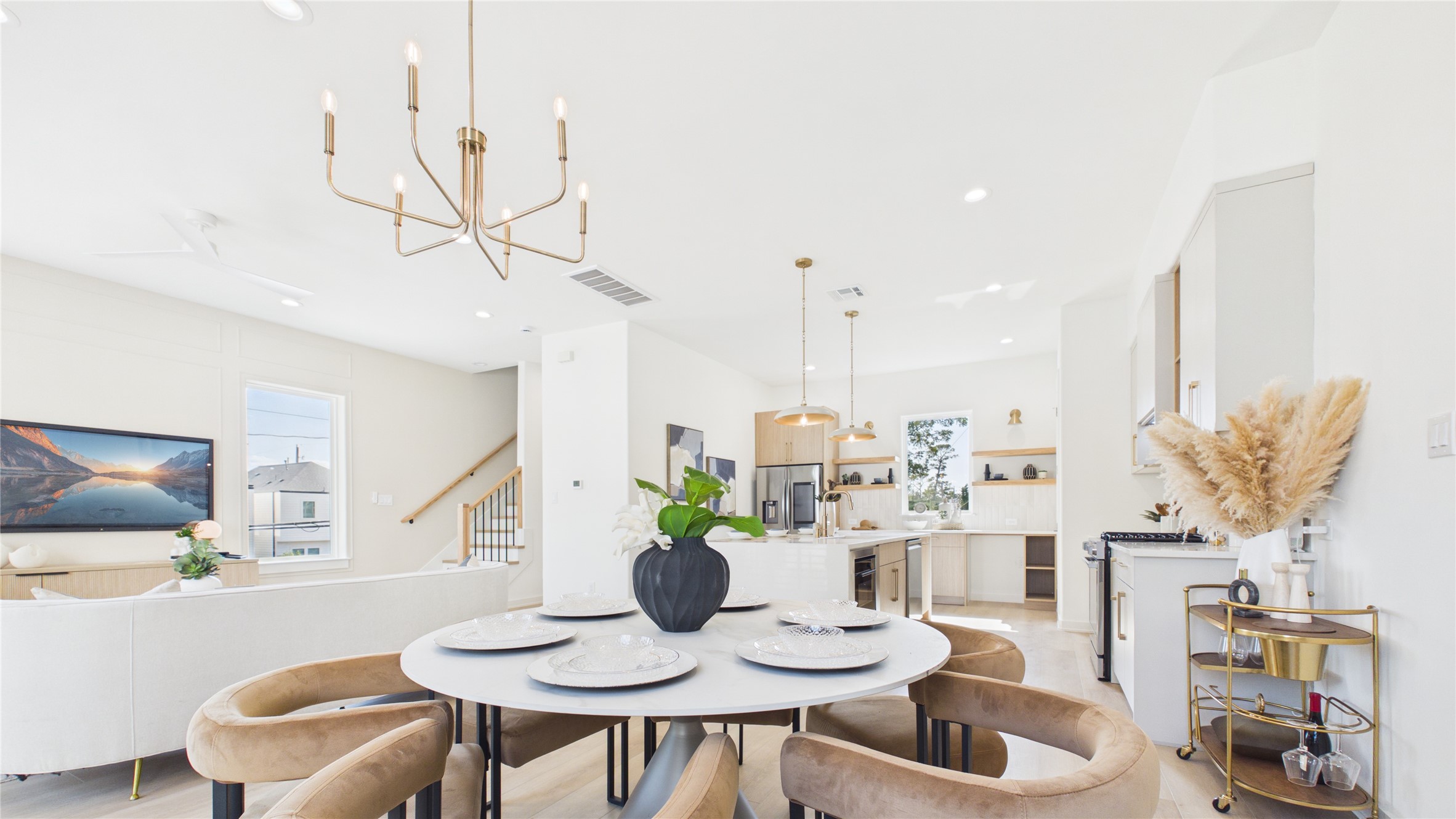 Bright open-concept living area with a stylish dining space, modern kitchen, and elegant lighting fixtures, perfect for entertaining.
