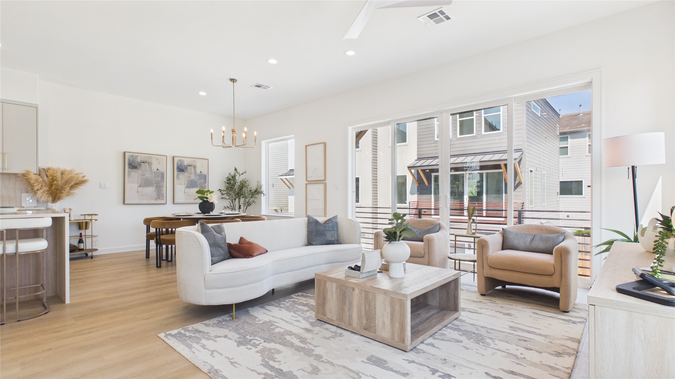 Airy open-concept living space featuring large windows and elegant light fixtures, seamlessly connecting the living and dining areas.