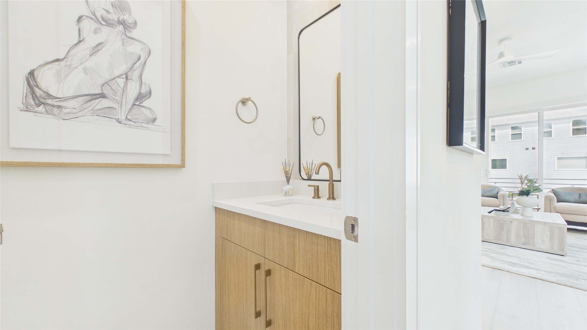 Modern half bathroom features a sleek wooden vanity with brass fixtures. Located on the second floor away from the kitchen.