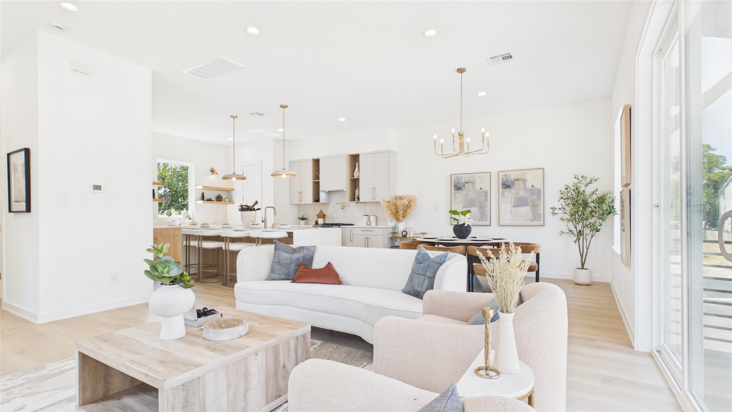 Open-concept living space featuring a sleek kitchen with an oversized island and a cozy dining area, all enhanced by abundant natural light.
