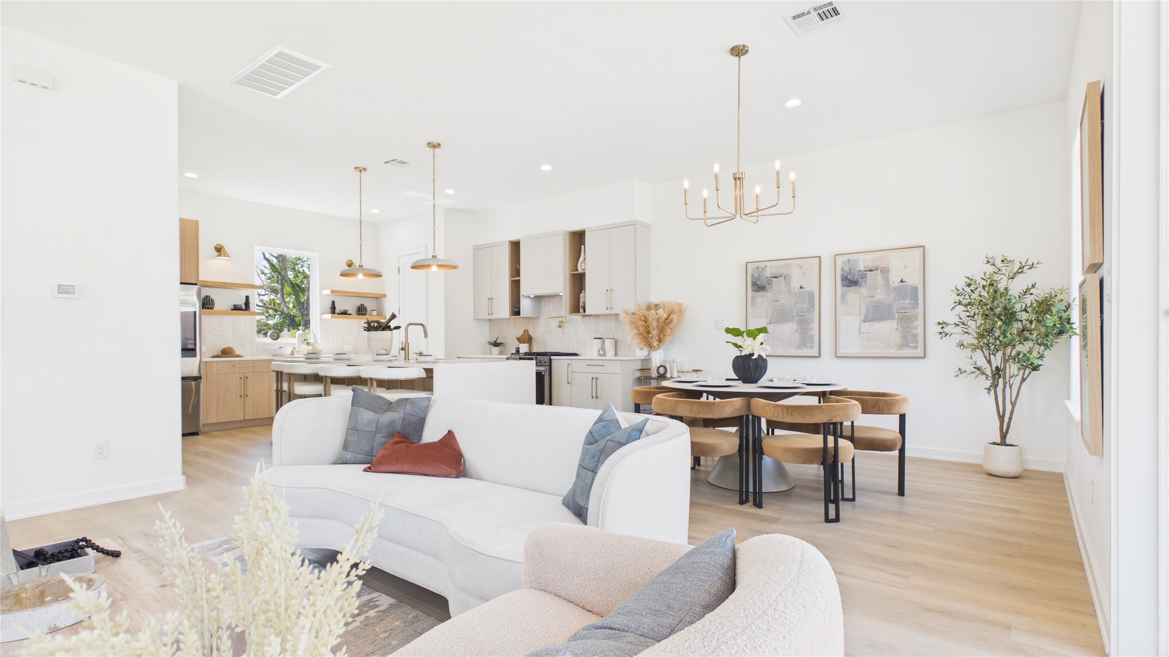 Bright and airy open-concept living area with modern kitchen, elegant dining space, and cozy seating, featuring sleek finishes and warm wood accents.
