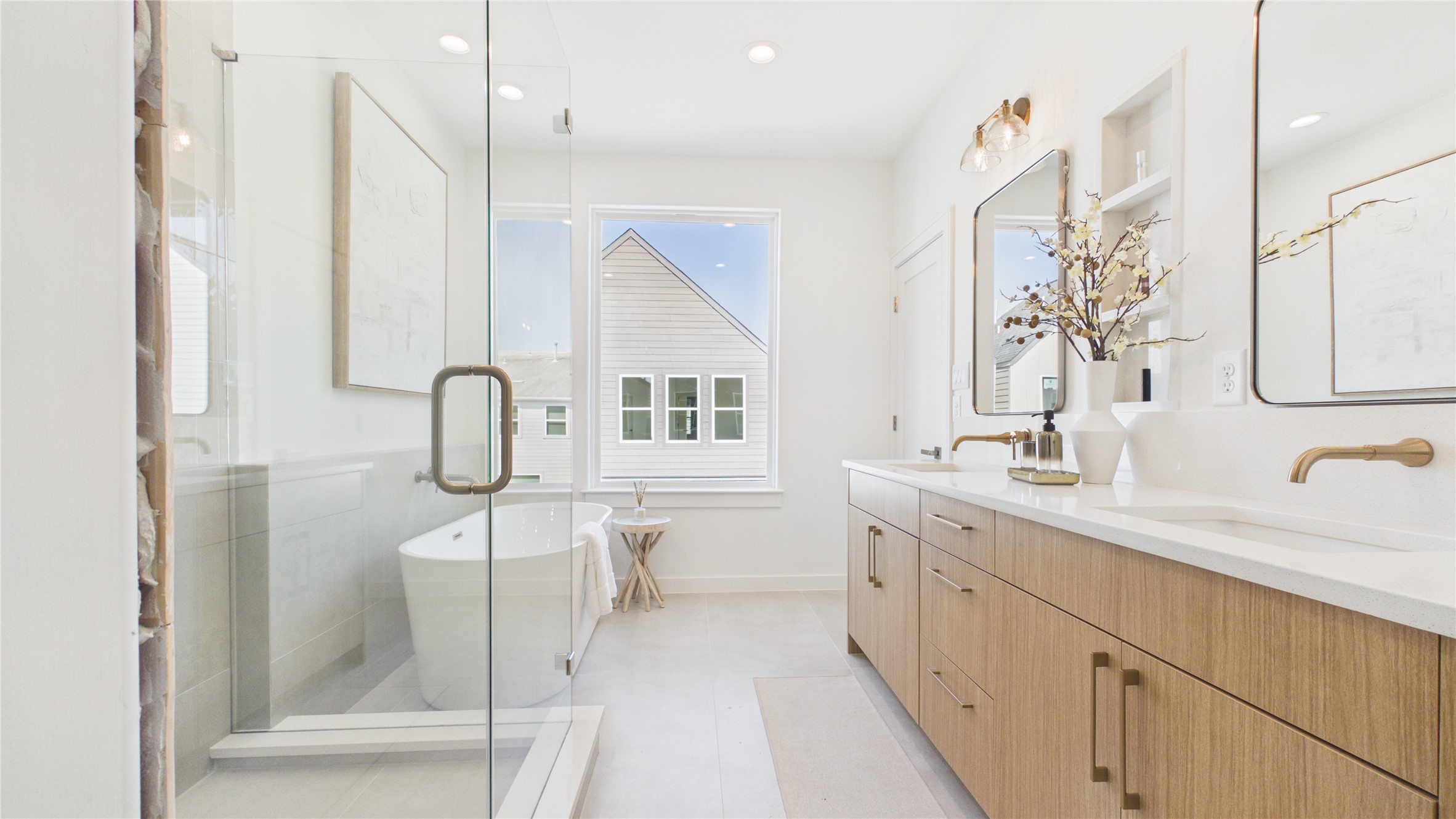 Bright and airy bathroom featuring a spacious glass-enclosed shower, elegant freestanding tub, and dual-sink vanity with modern fixtures.