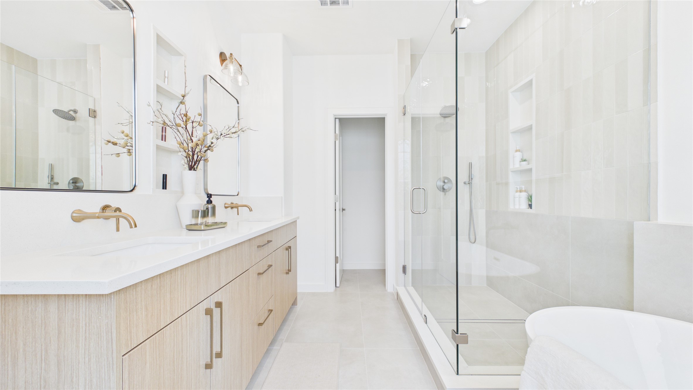 Bright and luxurious bathroom featuring a double vanity with elegant fixtures, and quartz niches.
