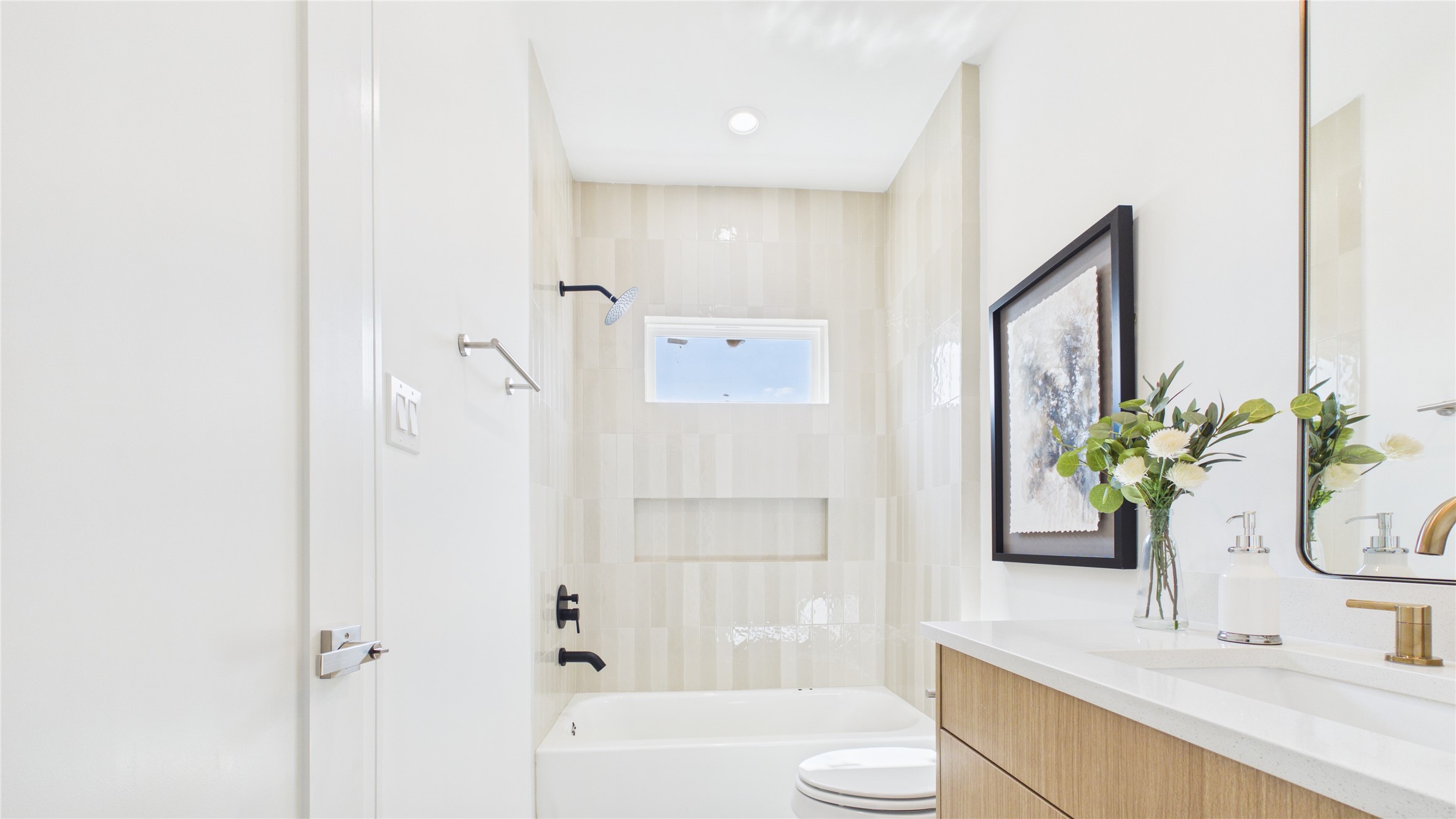Bright and modern bathroom featuring a sleek, light-toned tile shower, elegant fixtures, and a stylish vanity with fresh accents.