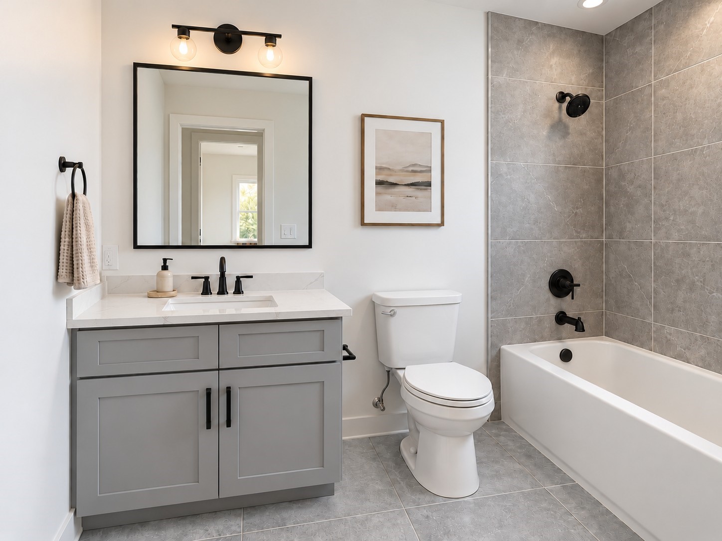 This beautifully appointed bathroom combines modern sophistication with everyday functionality. A stylish gray vanity features shaker-style cabinetry, a white countertop, an undermount sink, and matte black hardware. The large black-framed mirror and contemporary vanity lighting enhance the bright, welcoming atmosphere. A spacious bathtub surrounded by elegant textured tile provides the perfect place to unwind. These photos have been virtually rendered for visual reference. This beautifully appointed bathroom combines modern sophistication with everyday functionality. A stylish gray vanity features shaker-style cabinetry, a white countertop, an undermount sink, and matte black hardware. The large black-framed mirror and contemporary vanity lighting enhance the bright, welcoming atmosphere. A spacious bathtub surrounded by elegant textured tile provides the perfect place to unwind. These photos have been virtually rendered for visual reference.