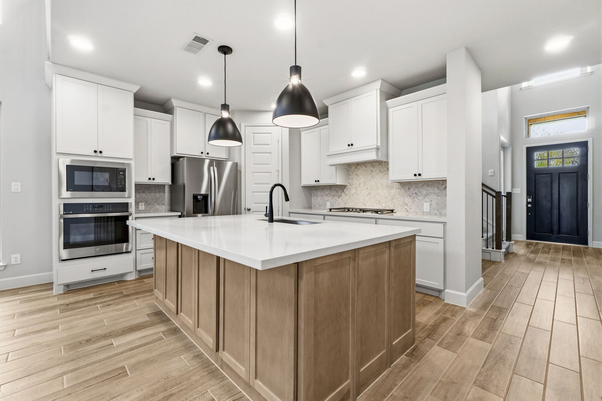 The beautifully designed kitchen features elegant quartz countertops, a designer tile backsplash, 5-Burner gas stovetop, stylish pendant lighting, an oversized island with abundant storage, and ample cabinetry to keep everything organized.