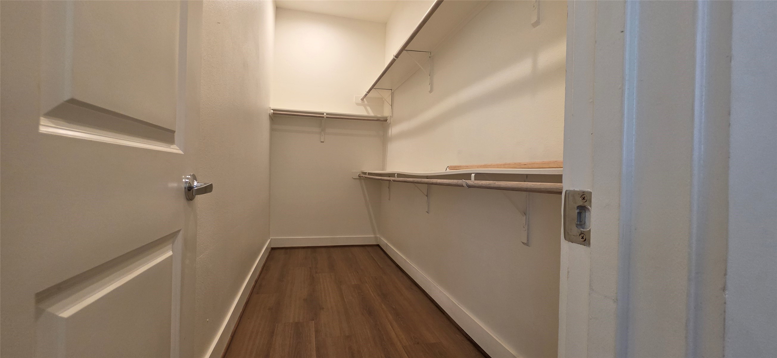 Primary bedroom closet with laminate floors