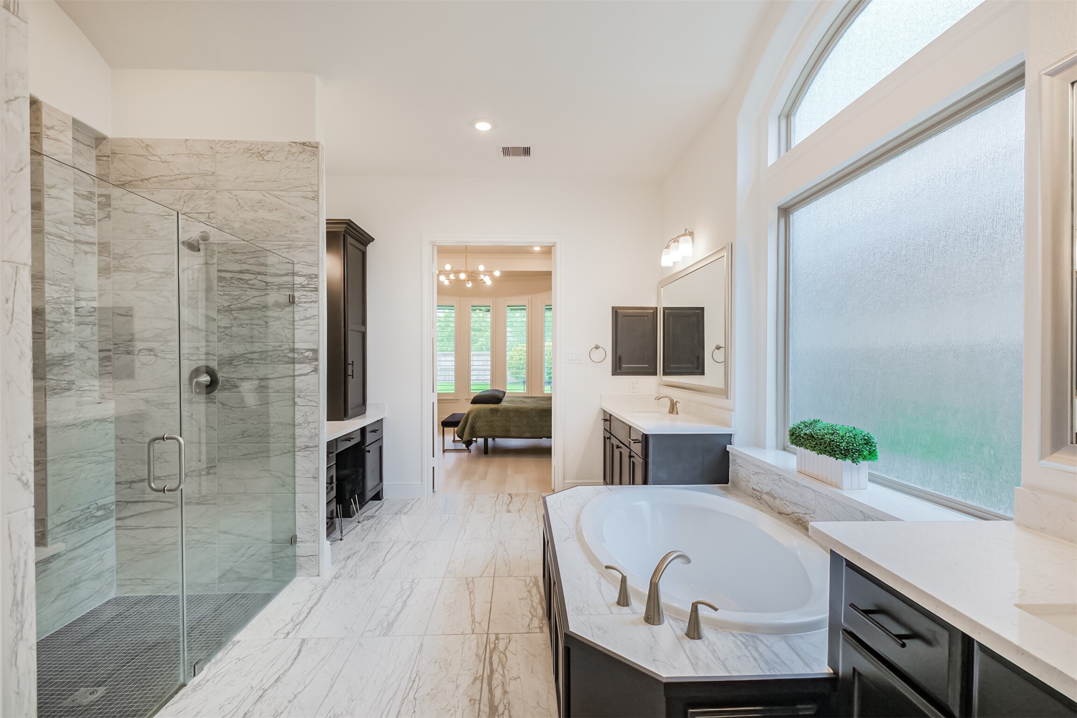 Lavish primary bathroom featuring an expansive walk-in shower, a grand soaking tub, and sleek dual vanities. Oversized frosted windows bathe the space in natural light while maintaining privacy, creating a serene, spa-inspired retreat.