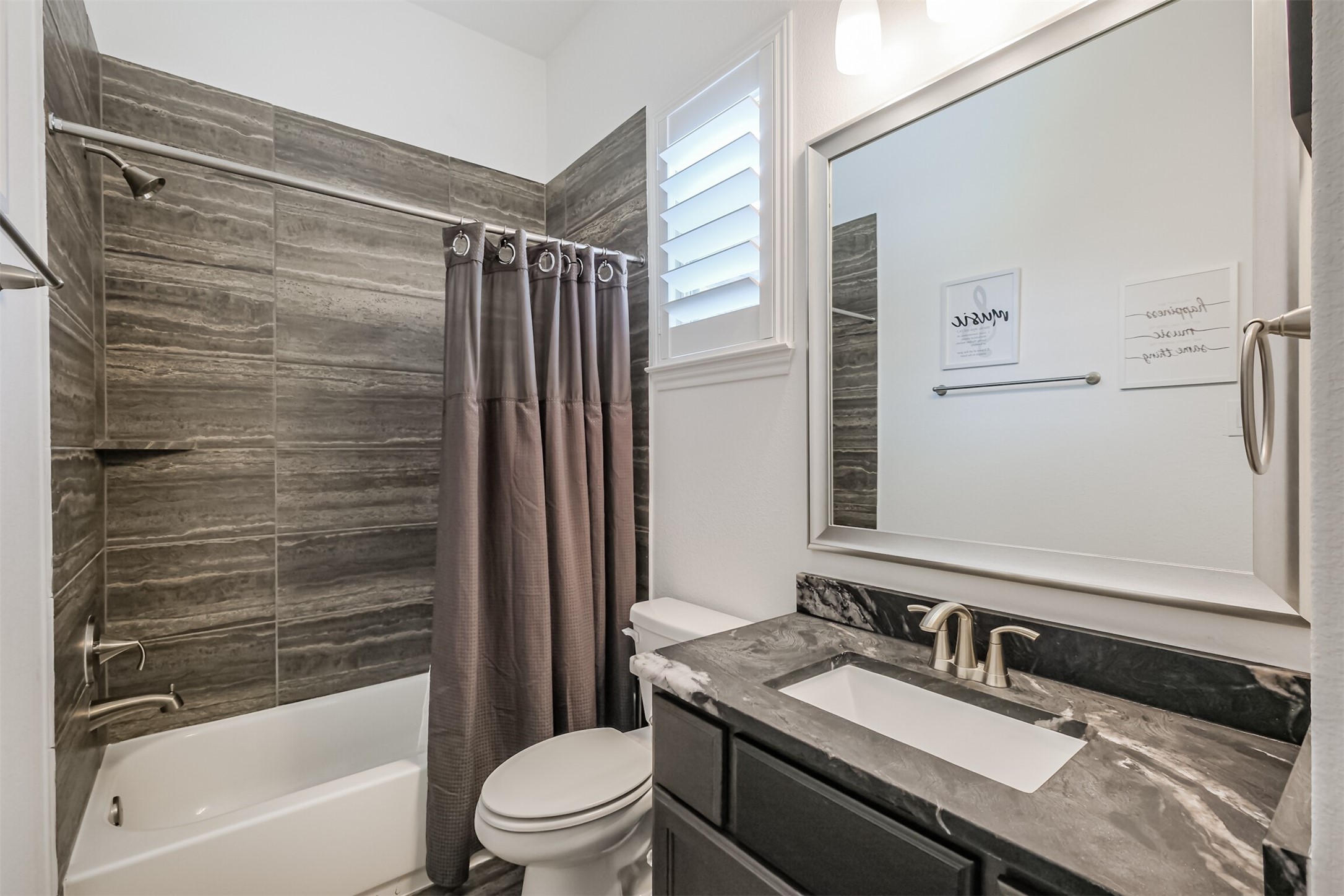 Well-appointed secondary bathroom within the private guest suite, featuring a sleek vanity with an elegant marble countertop, contemporary mirror, and a stylish shower-tub combination accented by modern tileworkoffering guests both comfort and privacy.